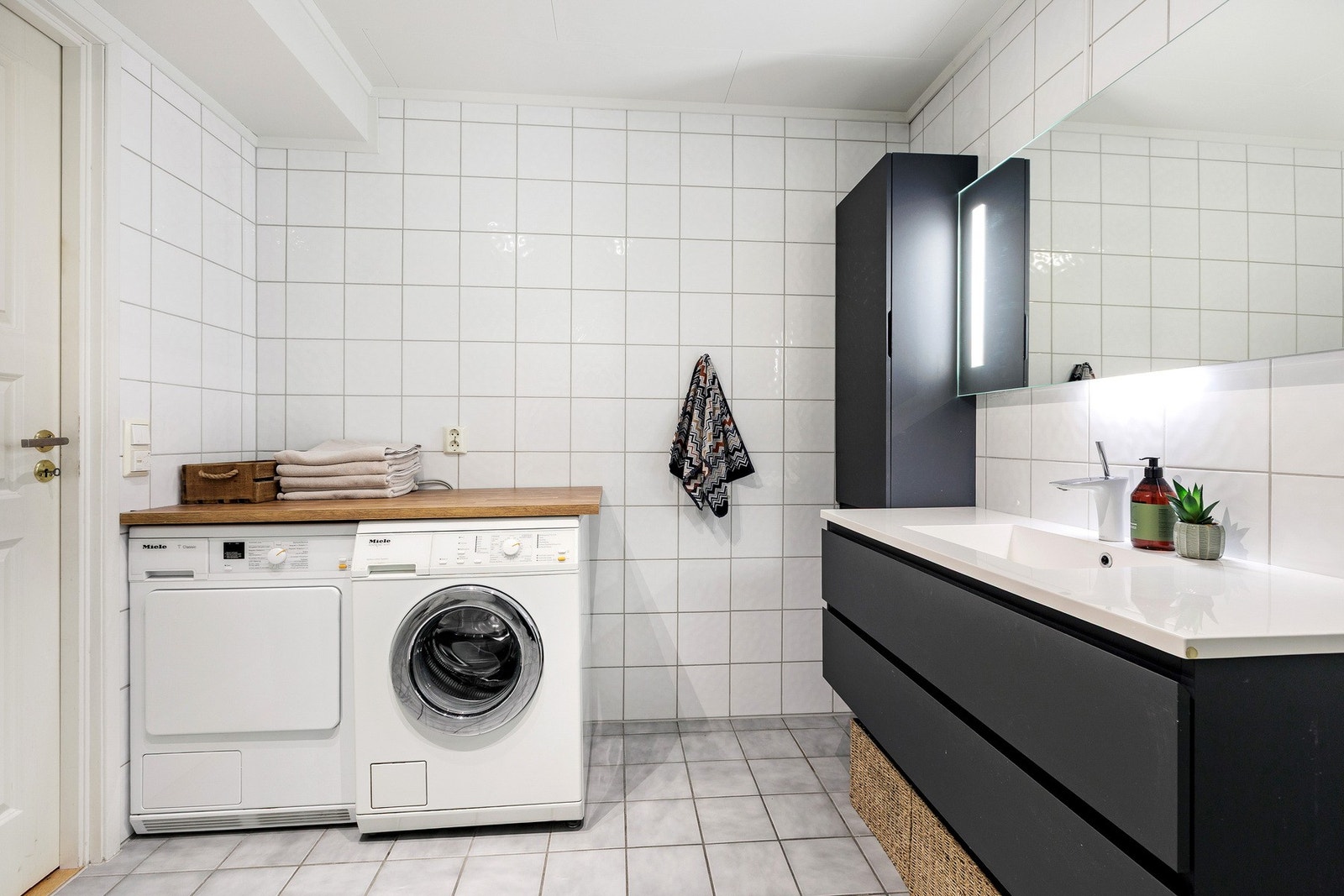 Badet har opplegg for vaskemaskin og tørketrommel. Benkeplate på toppen av disse. Galleribilde