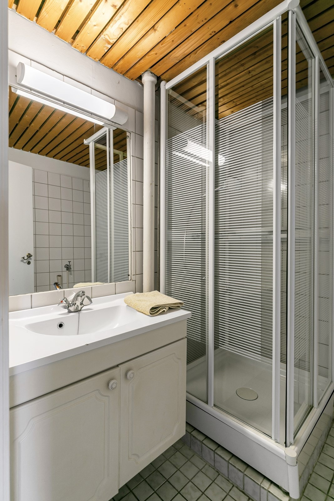 Badet har flislagt gulv med gulvvarme, dusjkabinett og opplegg for vaskemaskin. Galleribilde