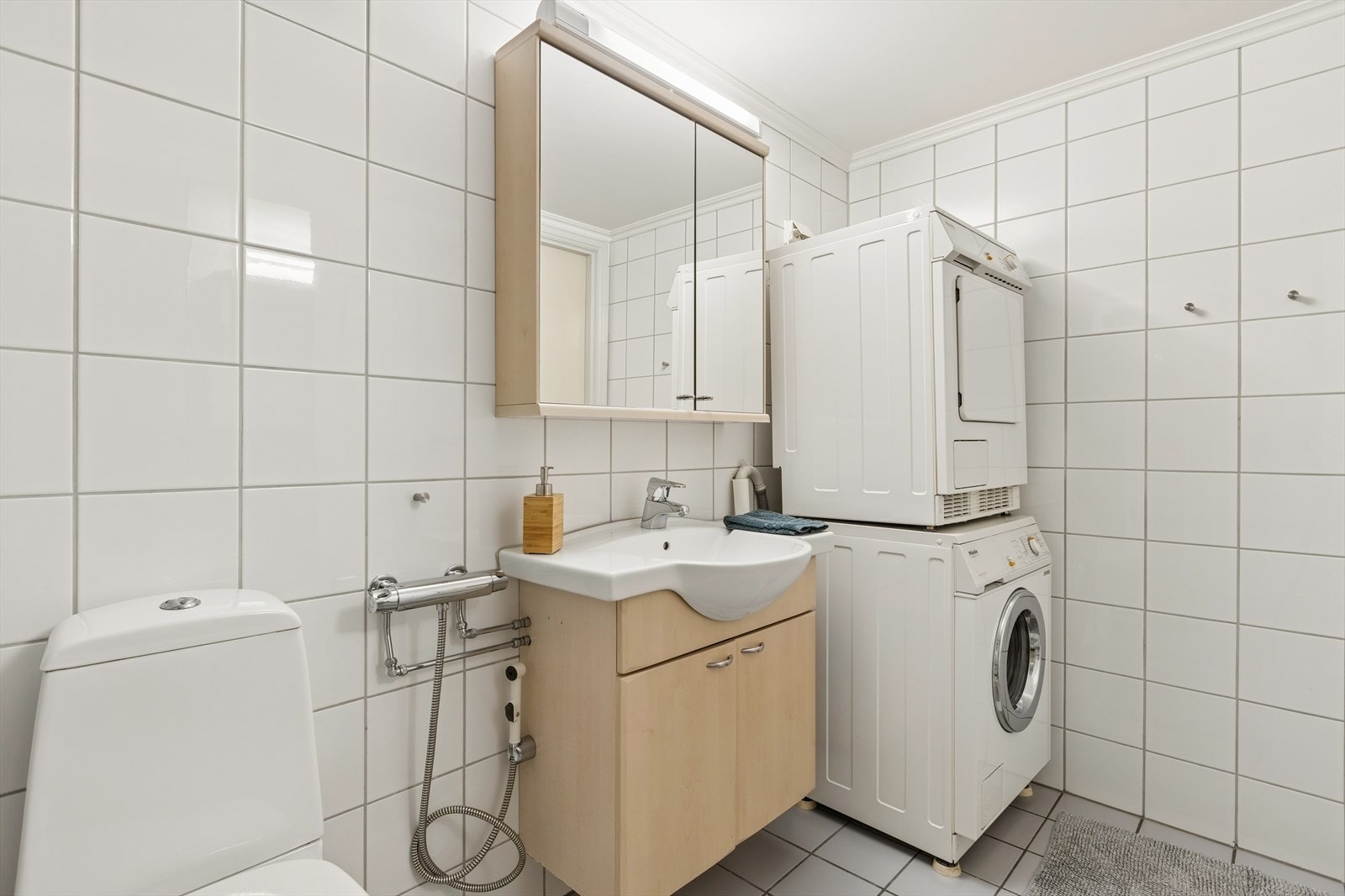 Videre er badet utstyrt med blant annet opplegg for vaskemaskin og tørketrommel, dusjkabinett, toalett og baderomsinnredning med oppbevaring. Galleribilde