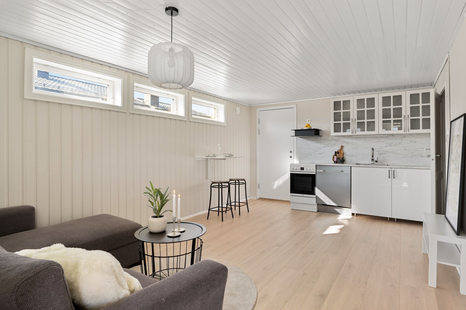 Åpen stue- og kjøkkenløsning i utleiedel. Sokkeletasjen har nylig blitt bruksendret og godkjent. Rommet får naturlig dagslys via tre kjellervindu og stort vindu i bakkant av sofaen. Hoveddel og utleie av egen bolig har intern forbindelse via intern dør. Galleribilde