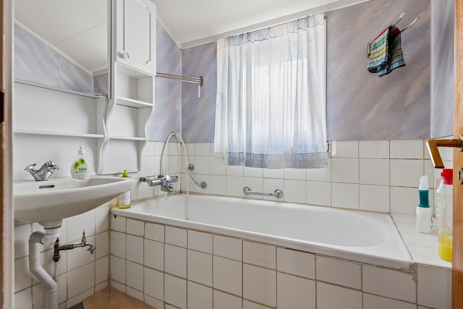 Badet er utstyrt med innebygget badekar, servant og baderomsplater på veggene. Galleribilde