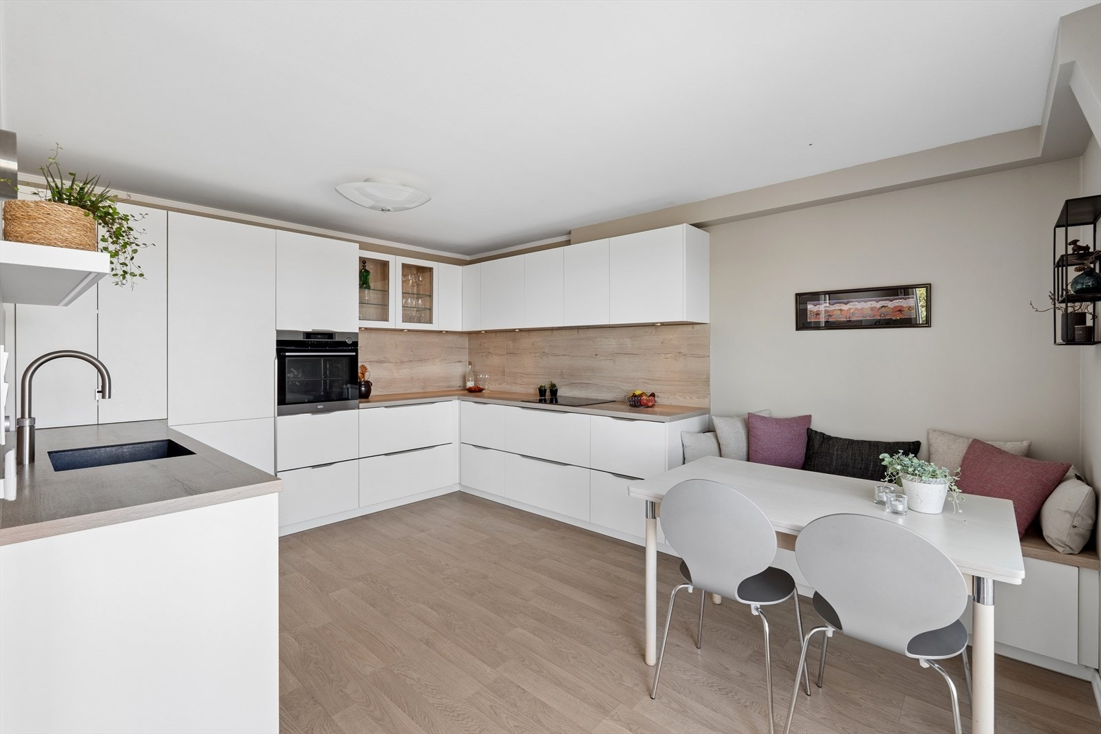 Moderne og stilren kjøkkeninnredning fra 2020 med lyse glatte fronter, slitesterk benkeplate i laminat og plassbygget sittebenk. Galleribilde