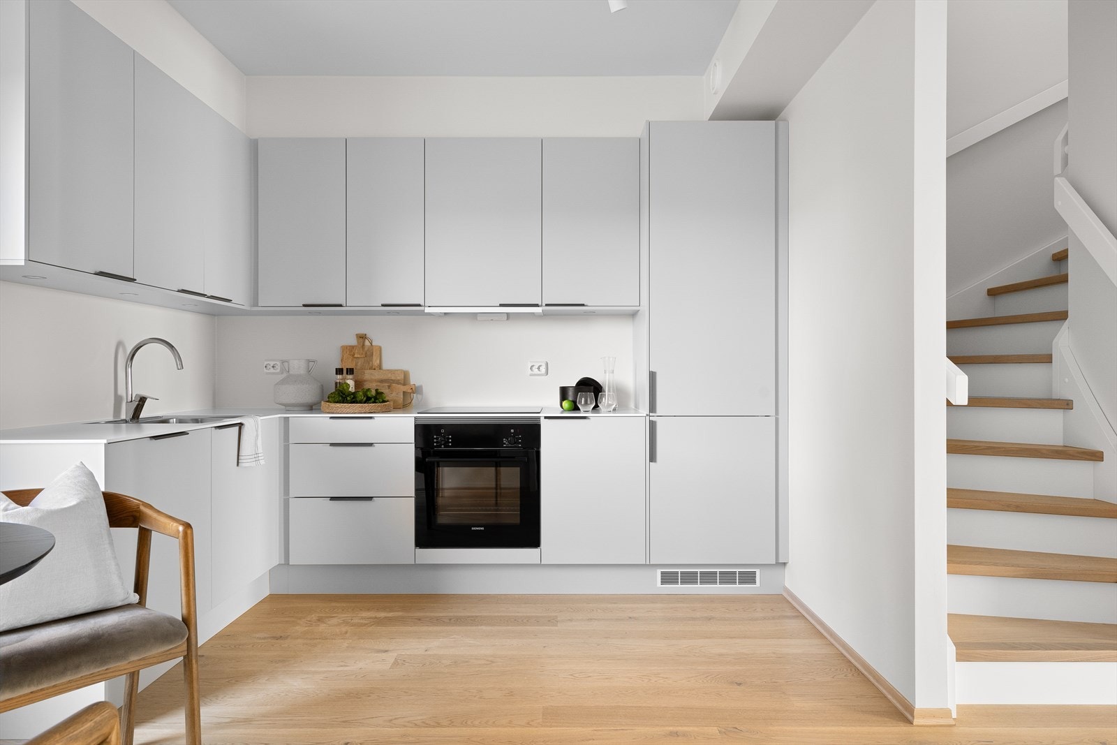 Kjøkkeninnredning i tidløst design kombinert med lyse overflater og en gjennomført helhet. Galleribilde