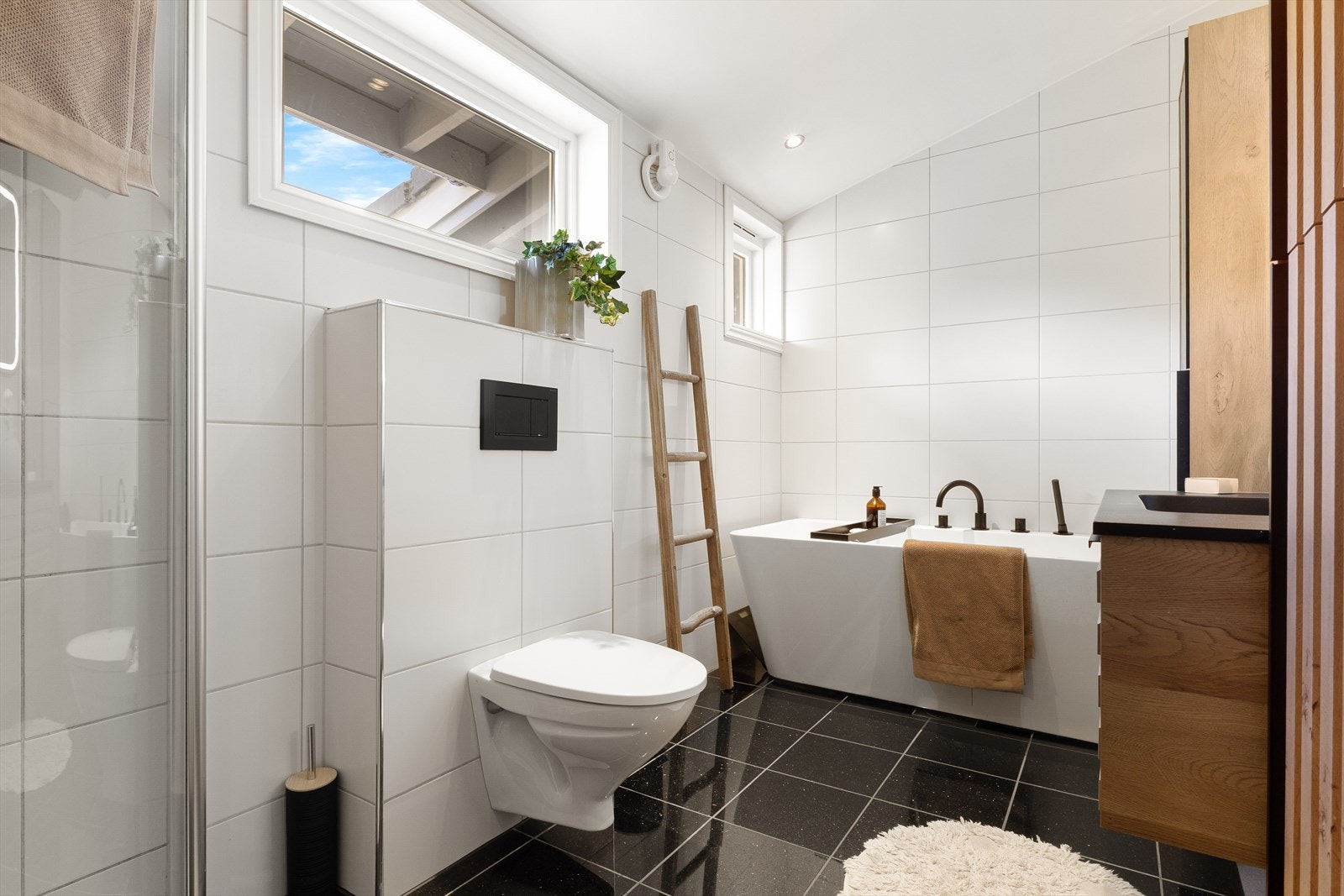 Badet er utstyrt med vegghengt toalett, dusj med inngående dører og badekar. Galleribilde