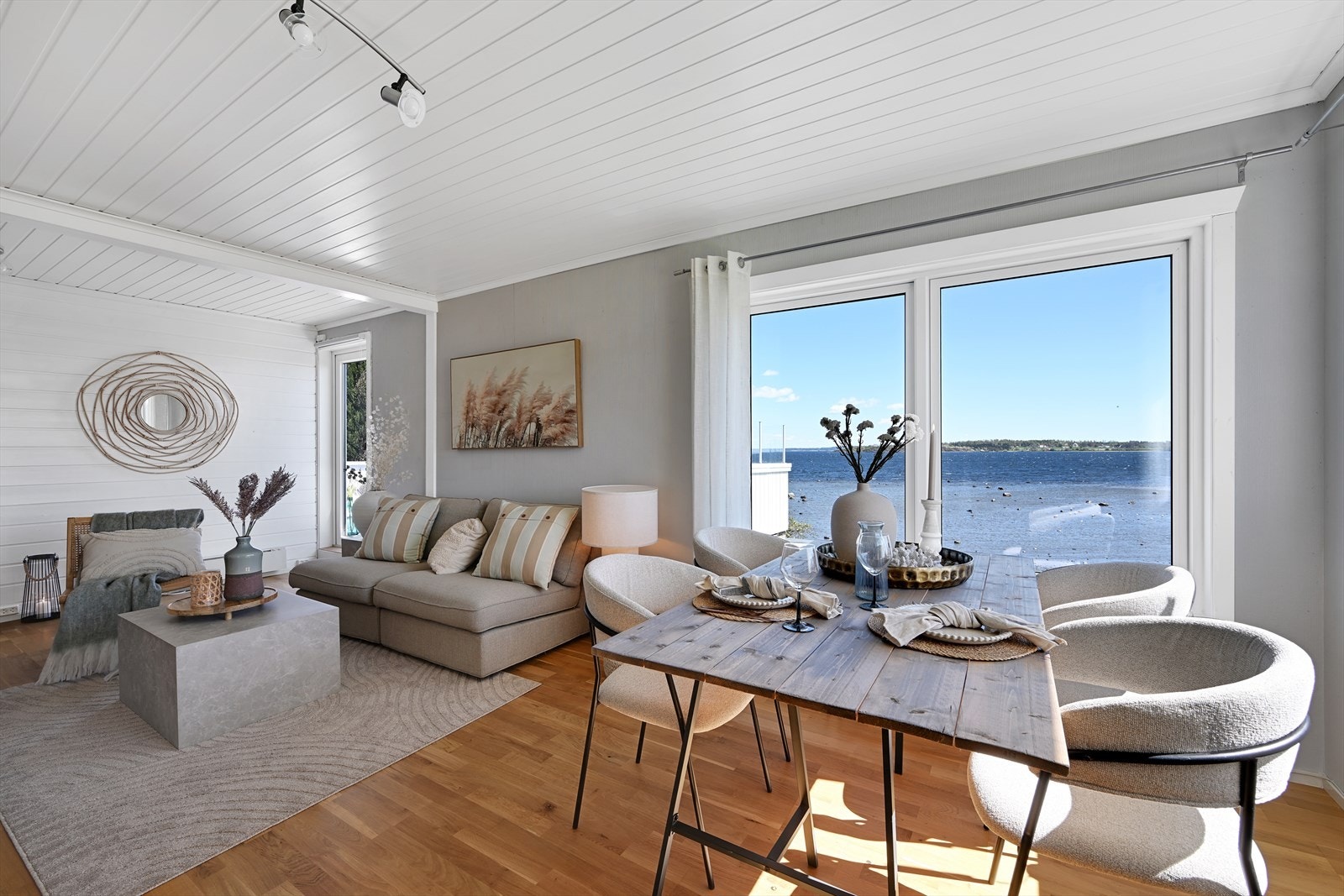 Stuen har god plass til både sofagruppe og spisebord, med parkett på gulv, tapet på veggene og malt panel i taket. Galleribilde