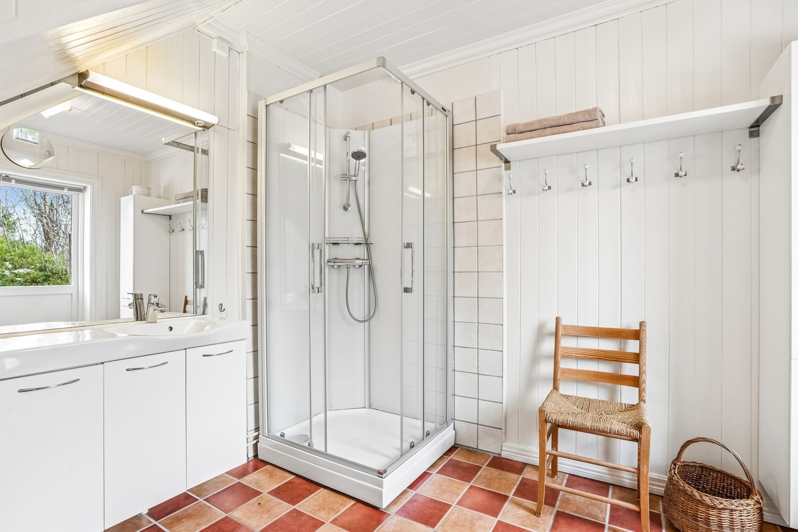 Bad innredet med toalett, dusjkabinett, vask, baderomsinnredning og opplegg for vaskemaskin. Galleribilde