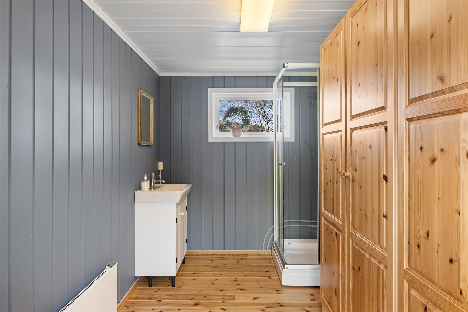 Badet er innredet med dusjkabinett, servant med underskap og rikelig med oppbevaringsplass. Galleribilde