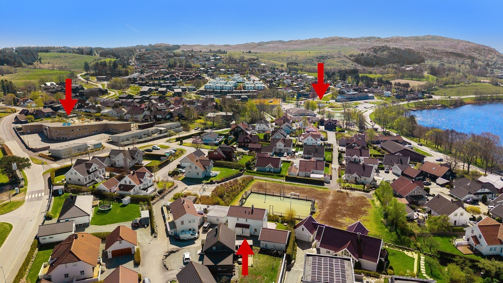 Høydefoto med pil mot huset nede i midten av bildet. Pil opp til høyre viser den korte veien det er ned til området der barne og ungdsomskolen ligger. Pil oppe til venstre viser ene barnehagen (Kvernaland Barnehage) som ligger like ved. Galleribilde