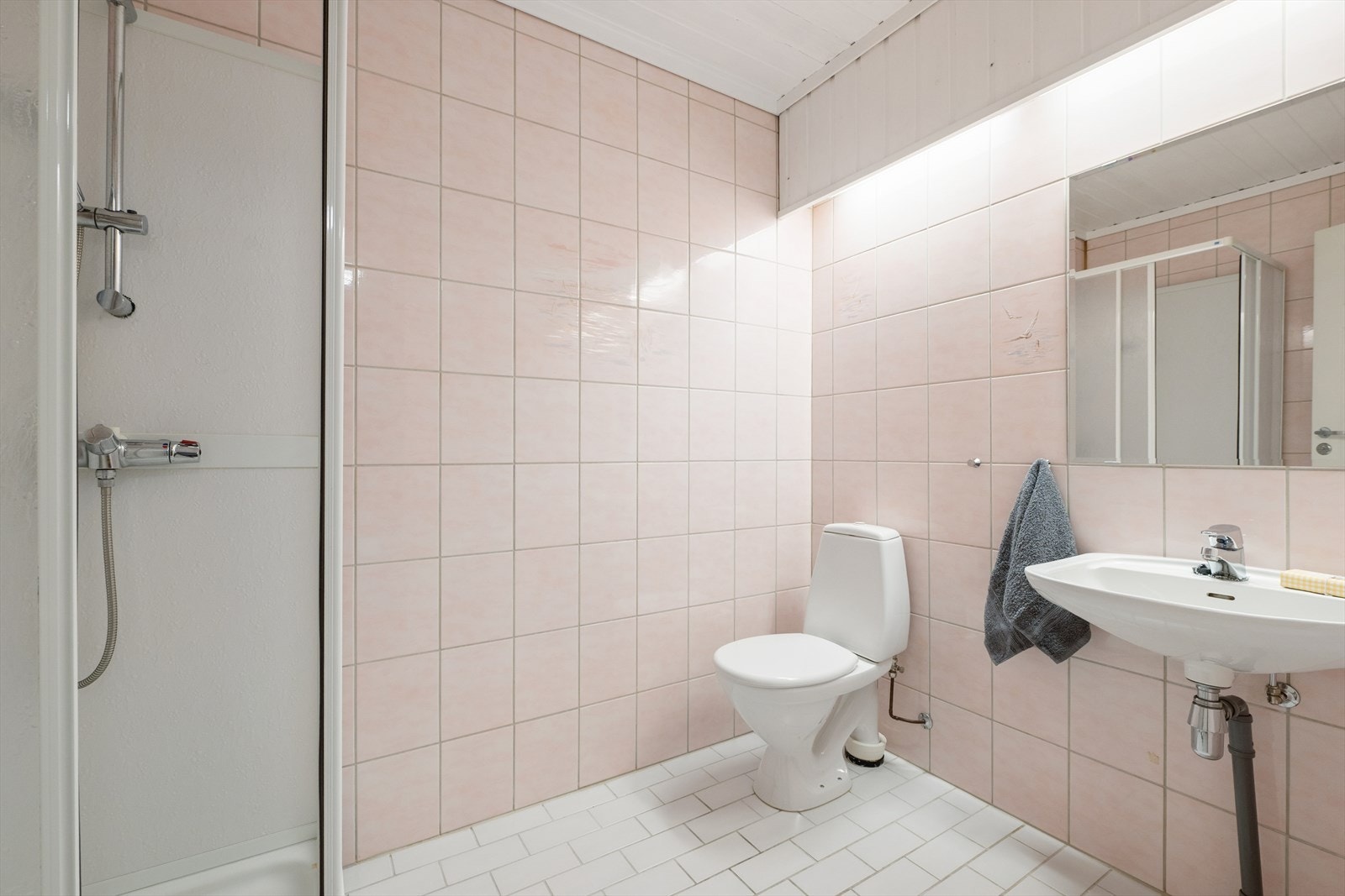 Badet i underetasjen er fra byggeåret og har fliser på gulv og vegger, samt dusjkabinett. Galleribilde