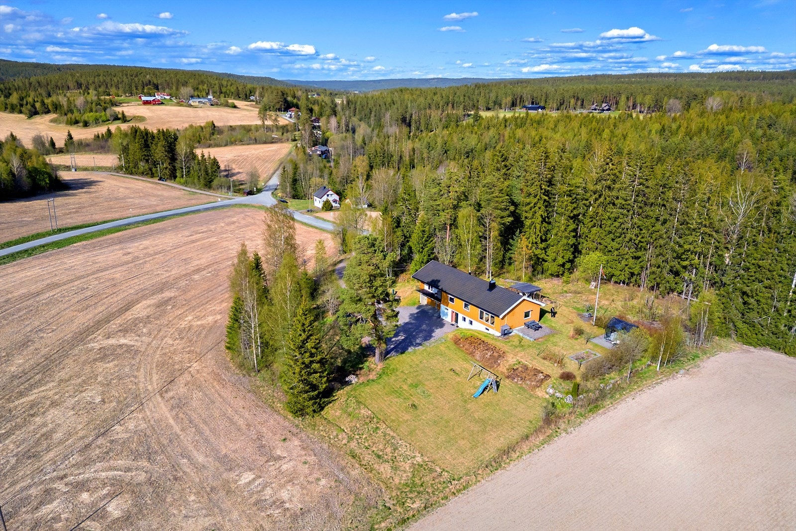 Eiendommen er pent opparbeidet med gruset innkjørsel, gressplen, busker, beplantning og flere sittegrupper. Galleribilde
