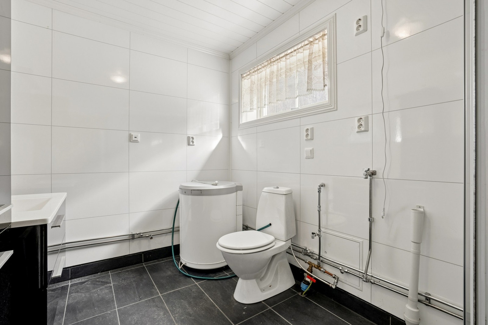 Badet er romslig og utstyrt med toalett, servantinnredning og opplegg for vaskemaskin. Galleribilde