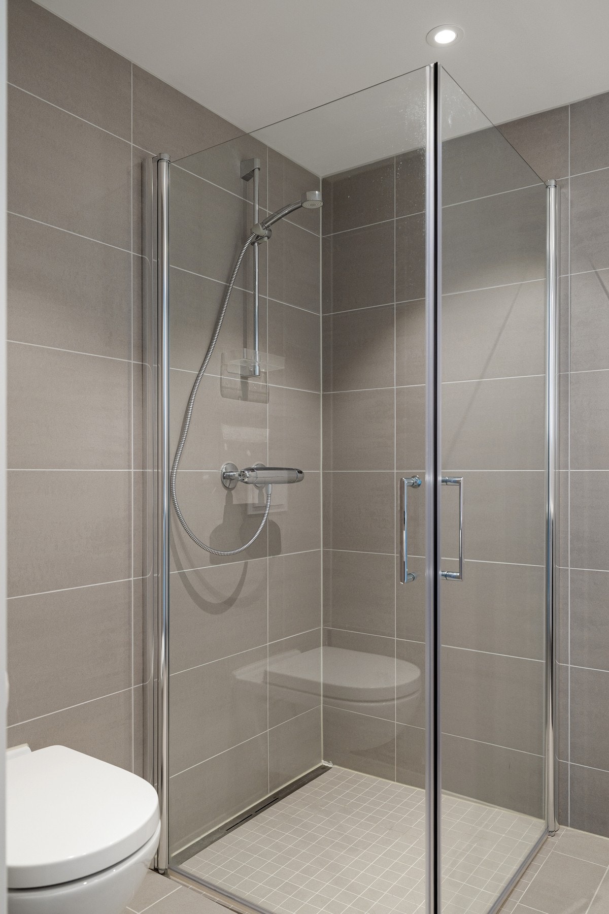 Videre har badet gulvvarme, vegghengt wc, fliser i tidsriktige fargetoner og downlights i himling som gir et rent uttrykk. Galleribilde