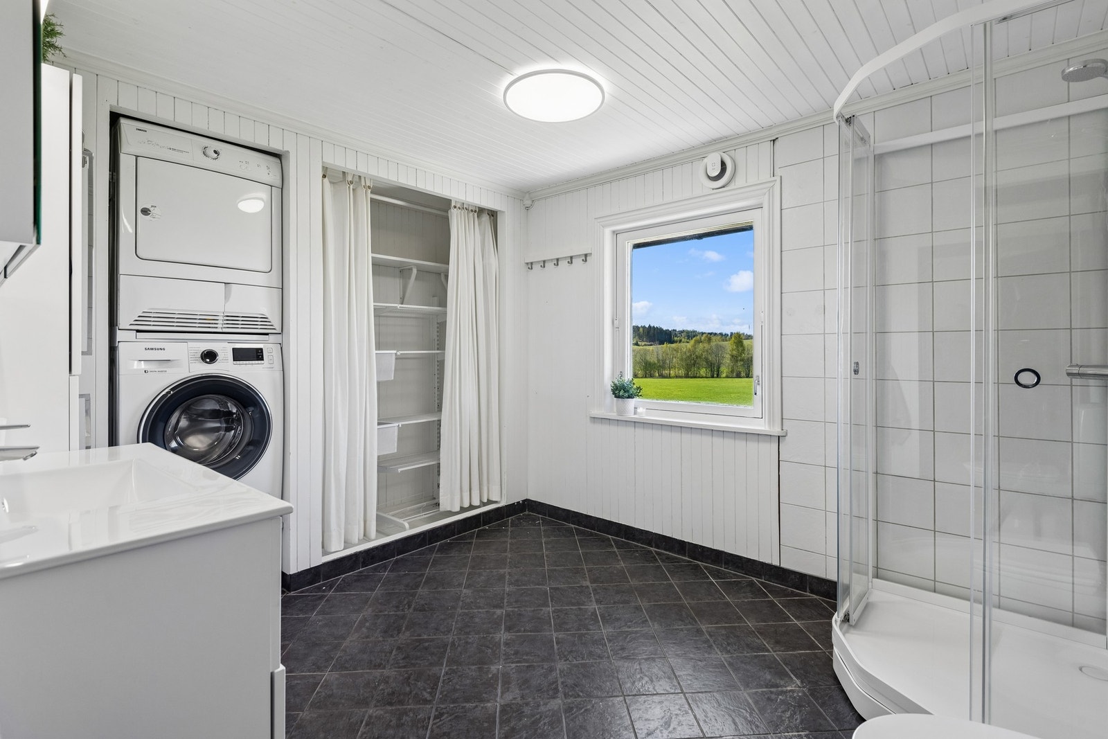 Romslig bad med praktisk plass til vaskemaskin og tørketrommel, samt innebygget garderobeløsning. Galleribilde