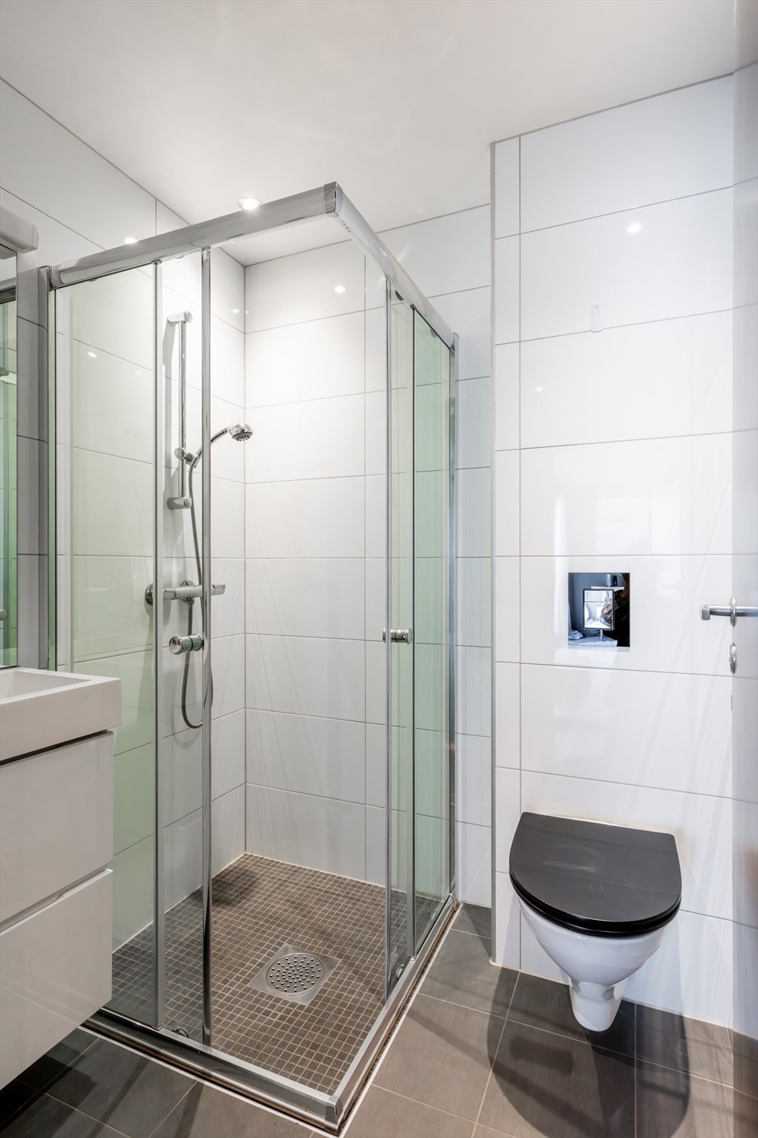 Praktisk bad nr. 2 med gulvvarme som gir god komfort. Badet er utstyrt med mekanisk avtrekk, dusjhjørne, veggmontert wc og servantskap med ettgreps blandebatteri fra Duxa. Galleribilde