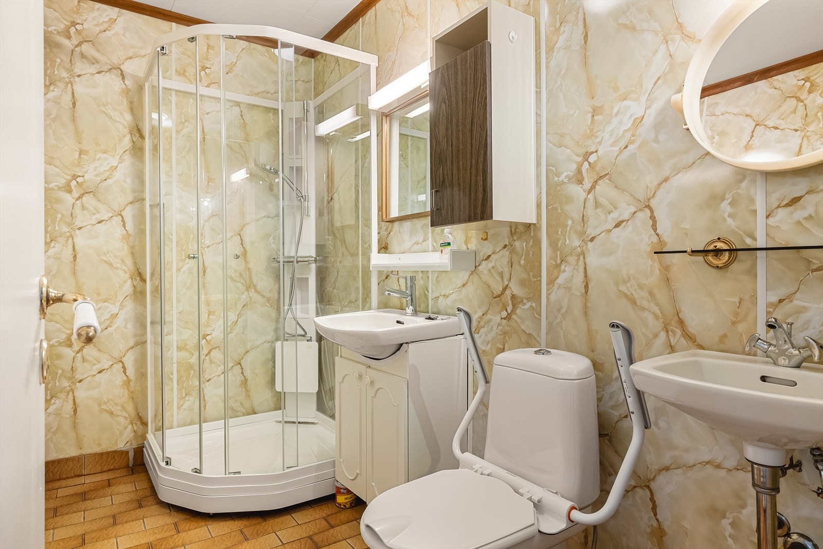 Badet (4 kvm) har fliser på gulv og baderomsplater på vegger. Inneholder servant med møblement, toalett og dusjkabinett. Badet ble modernisert og utvidet ca. 1975/1976, men fremstår i dag som utdatert. Dusjkabinett ble skiftet i 2021. Varmekabler i gulv. Galleribilde
