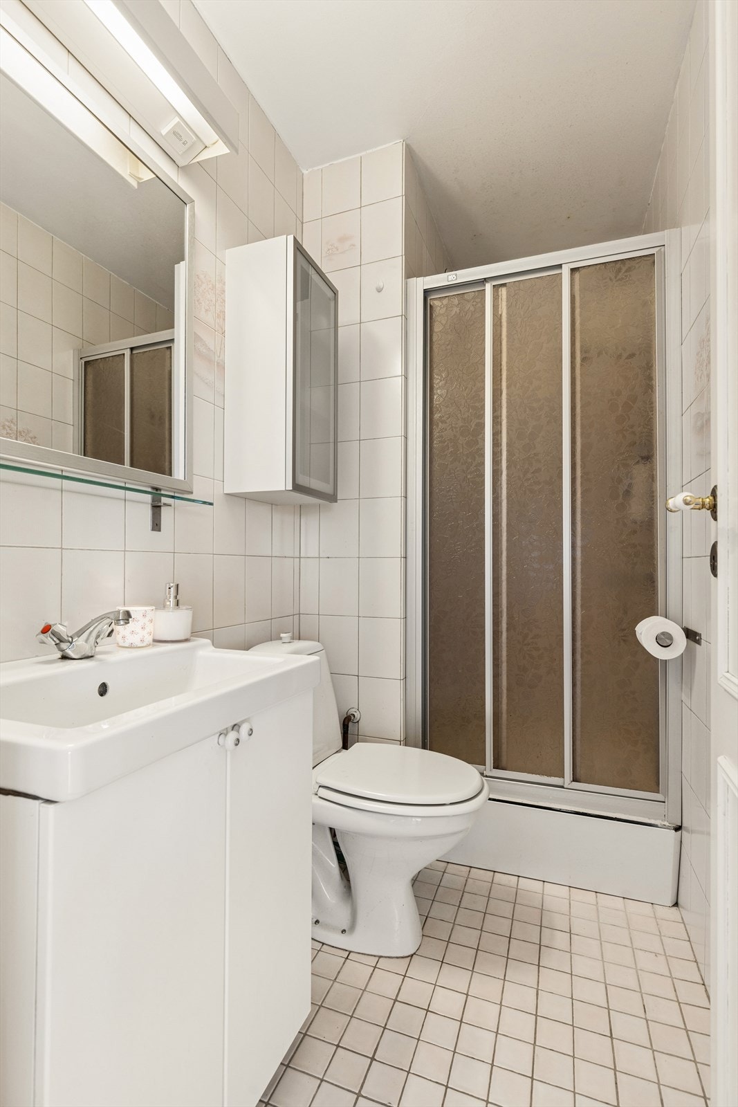 Det andre badet er innredet med nedfelt servant, toalett og dusjkabinett, og har flislagte vegger og gulv som gir et ryddig og klassisk uttrykk. Rommet har mekanisk avtrekk. Galleribilde