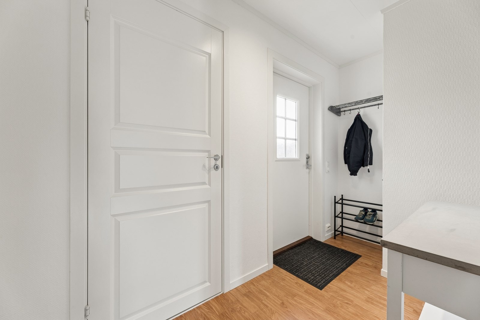 Entréen ønsker deg velkommen med gulvvarme og en ny, malt ytterdør fra 2023. Her er det gode oppbevaringsmuligheter med plass til oppheng av yttertøy og oppbevaring av sko, noe som gir en praktisk og ryddig entrésone. Galleribilde