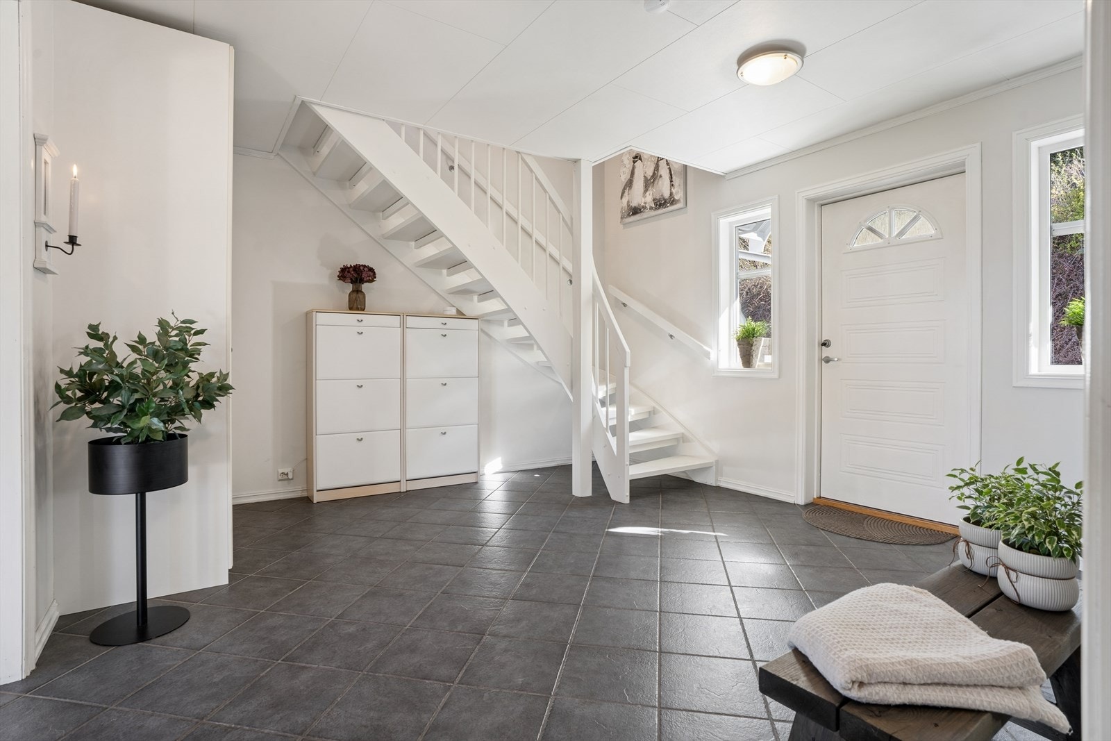 Lys og trivelig hall med flislagt gulv og trappeadkomst til boligens øverste plan, et innbydende førsteinntrykk. Galleribilde