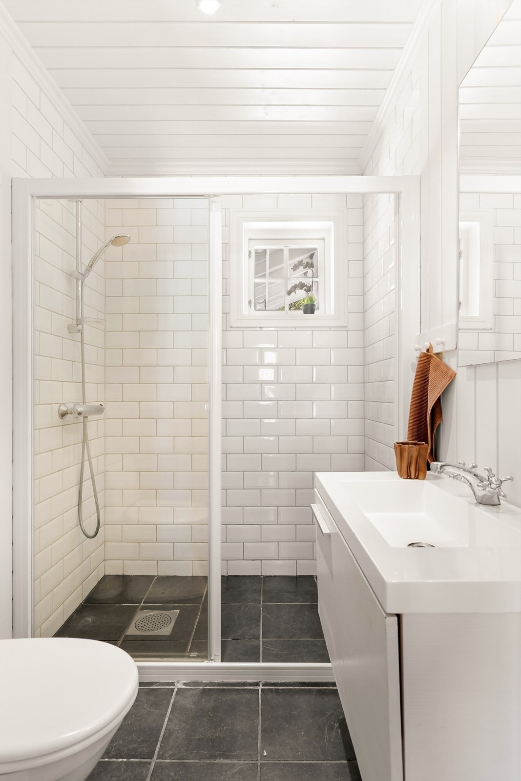 Badet i gjesteavdelingen har flislagt gulv med gulvvarme og dusjhjørne med glassvegger. Galleribilde
