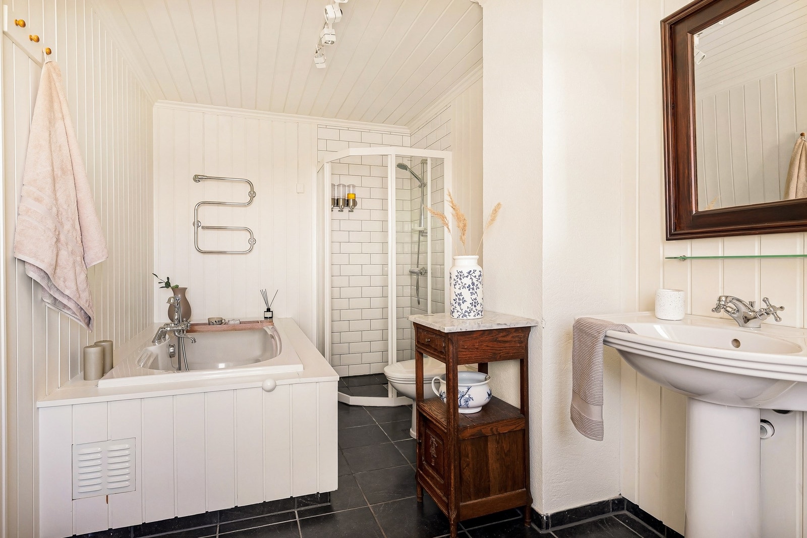 Badet er pent innredet i klassisk og tidløs stil med flis på gulv med varme, og panel på vegger. Galleribilde