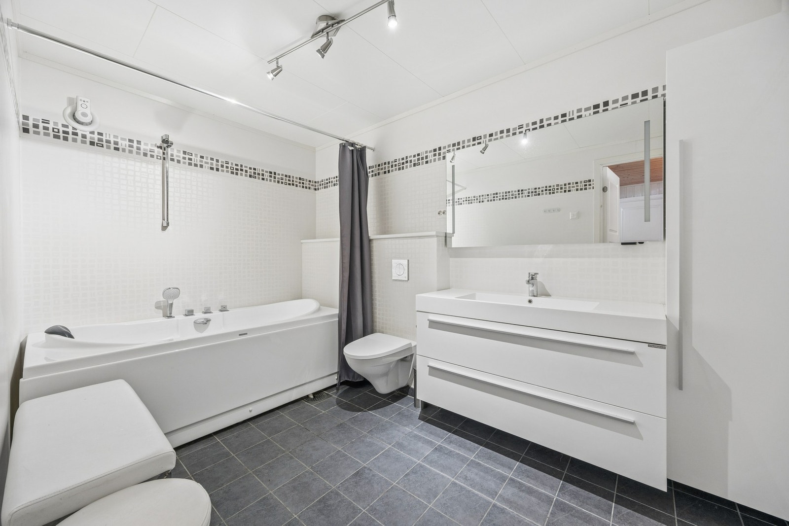 Dette badet har flislagt gulv med varmekabler og en elektrisk styrt vifte. Galleribilde