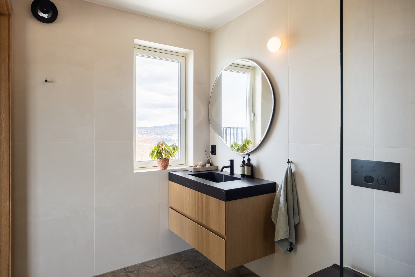 Badet fremstår som pent og påkostet med store fliser (60x120) på gulv og lyse veggfliser (60x60). Her er baderomsinnredning, vegghengt toalett og dusjnisje. Dusjgarnityr/blandebatteri fra Primy. Galleribilde