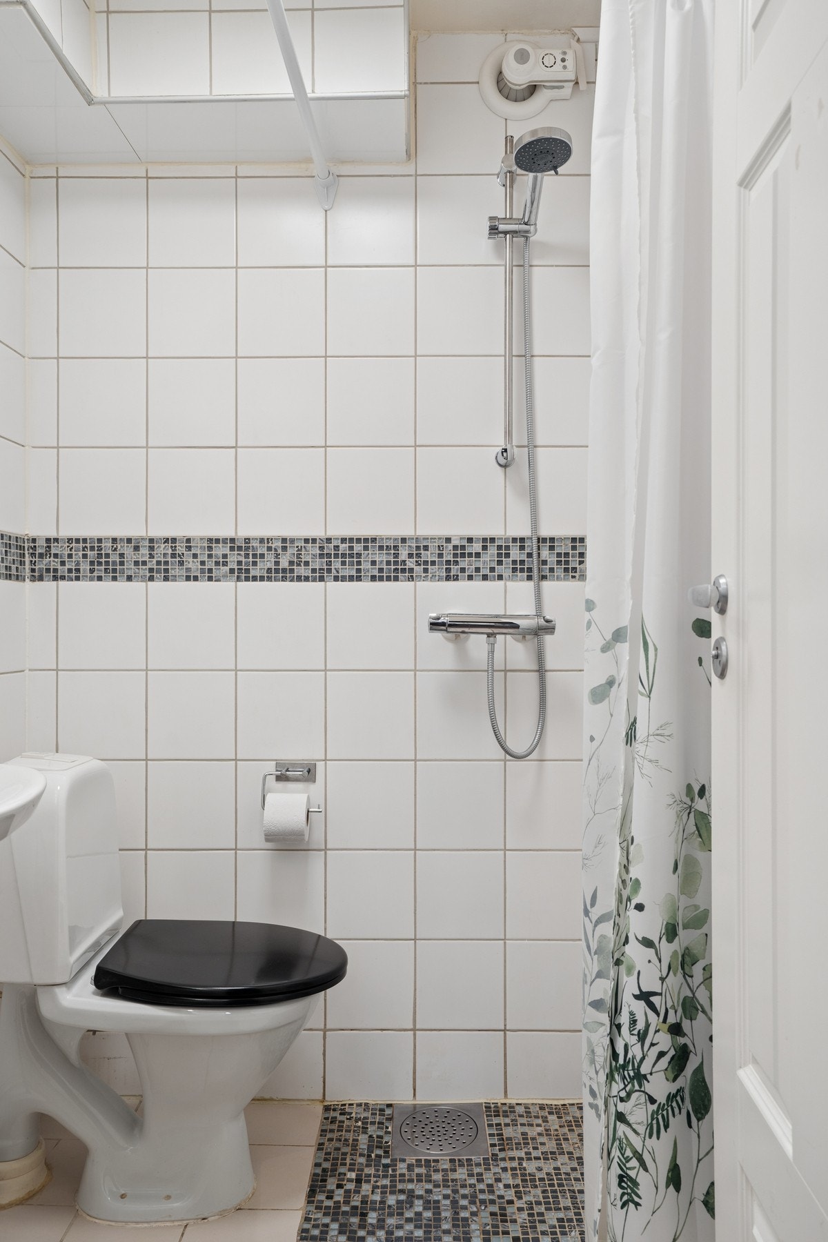Badet er utstyrt med dusjhjørne, servant med oppbevaring og toalett. Galleribilde