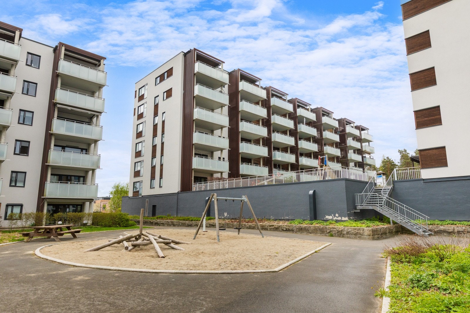 Felles tomt som er opparbeidet med busker, trær, plenområder, diverse beplantning, sykkelparkering, sittegrupper og asfalterte internveier. Galleribilde