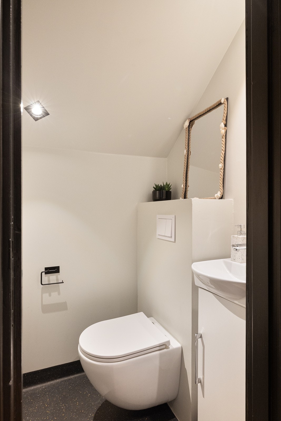 Vegg i vegg med badet ligger et toalettrom. Rommet har belegg på gulv, samt malte glatte flater på vegger og i tak. Videre er rommet innredet med vannklosett, underskap ned servant og speil. Galleribilde