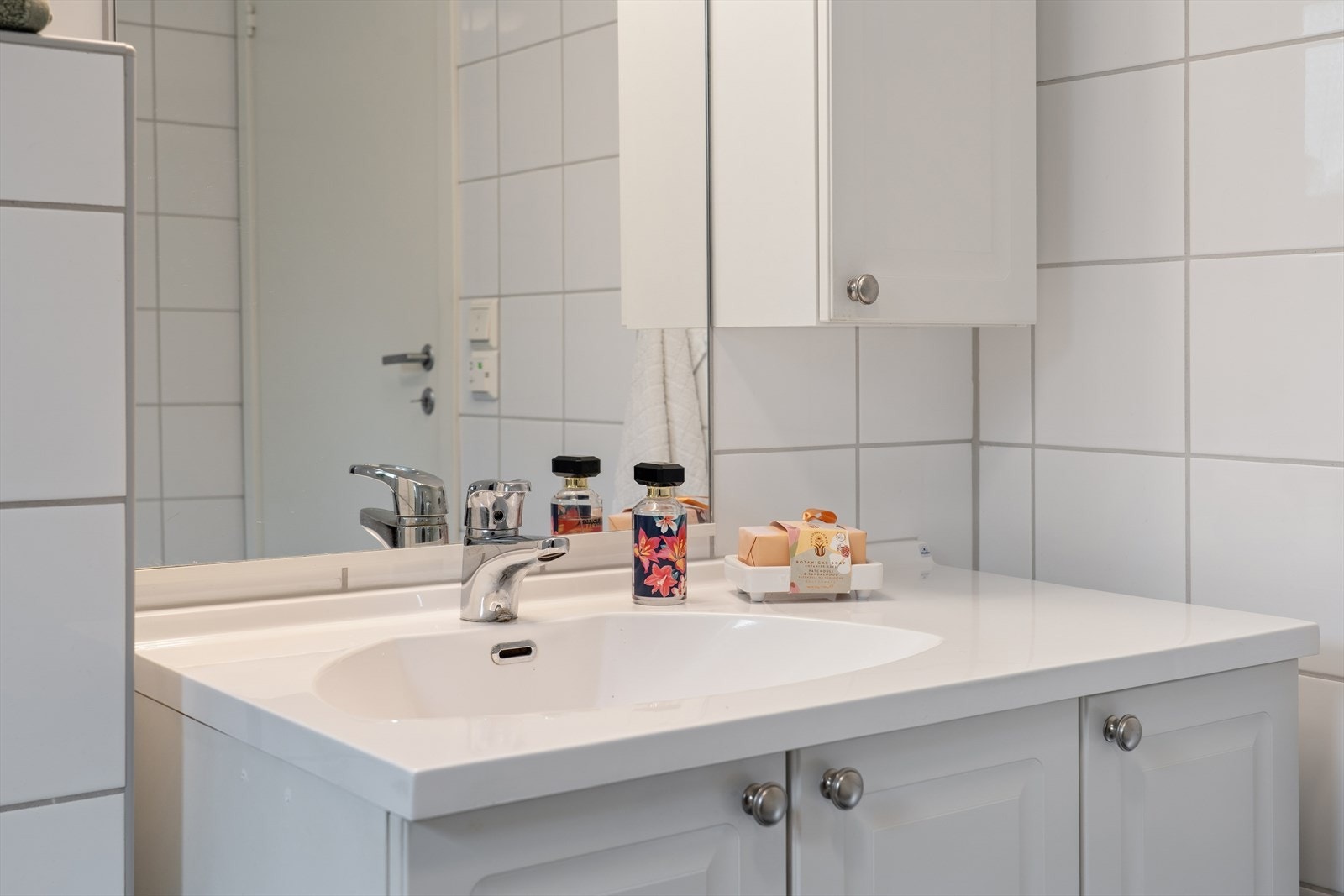 Badet er innredet med nedfelt servant, veggmontert toalett, dusjvegger/hjørne og opplegg for vaskemaskin. Galleribilde