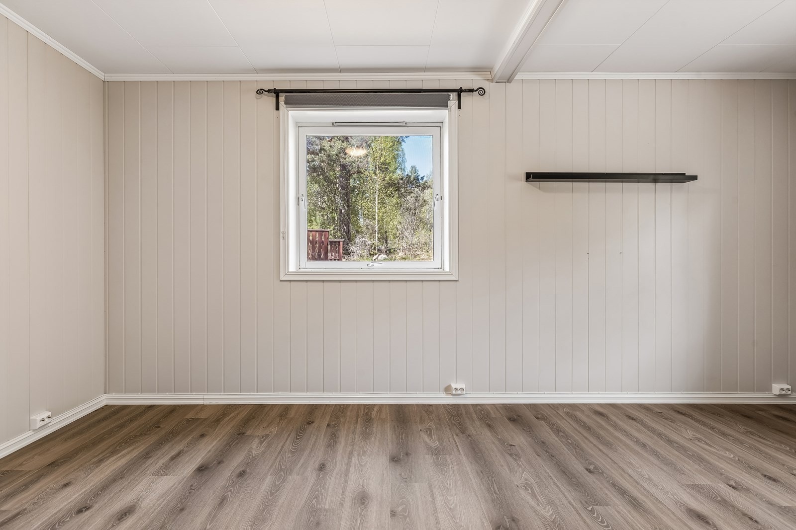 Soverom med vegger kledd i trepanel og laminat på gulvet. Galleribilde