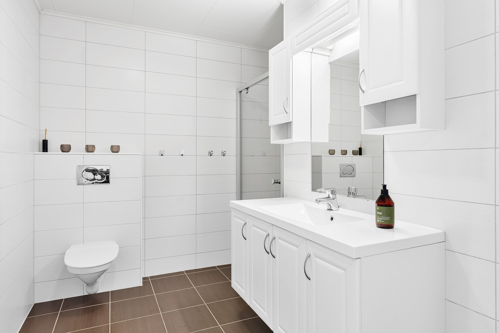 Badet er helfliset med dusjnisje, vegghengt toalett og romslig innredning med over og underskap. Galleribilde