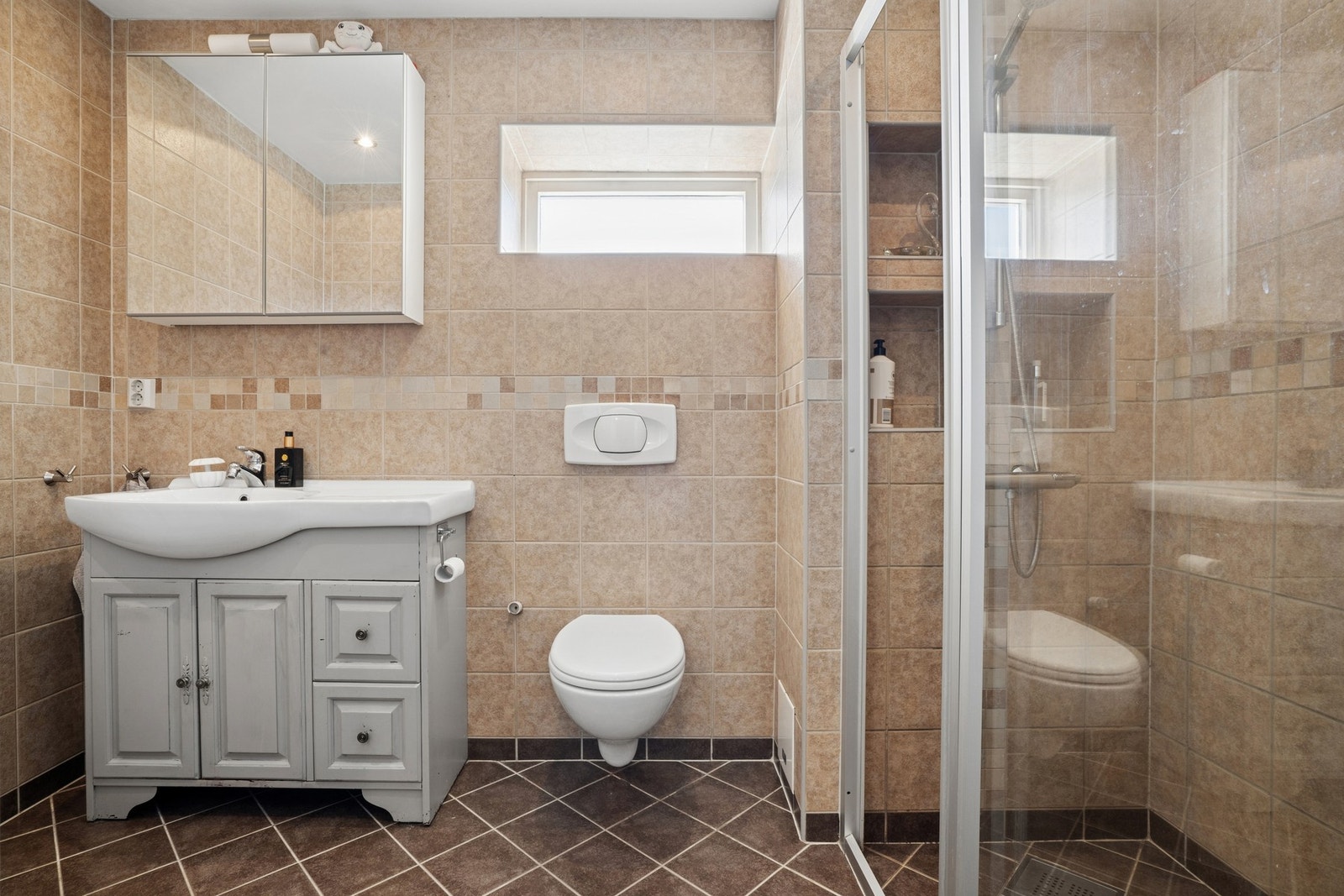 Badet har vegghengt WC, servant med under og overskap, dusjvegger i eget dusj hjørne. Galleribilde