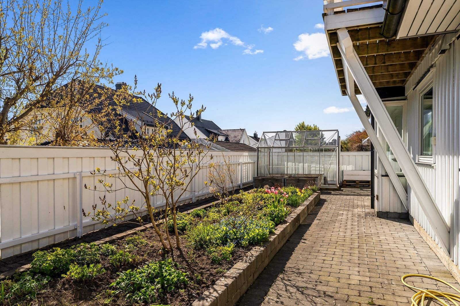 Blomstrende stauder og et grønt, levende uteområde som rammer inn eiendommen på en innbydende måte. Galleribilde