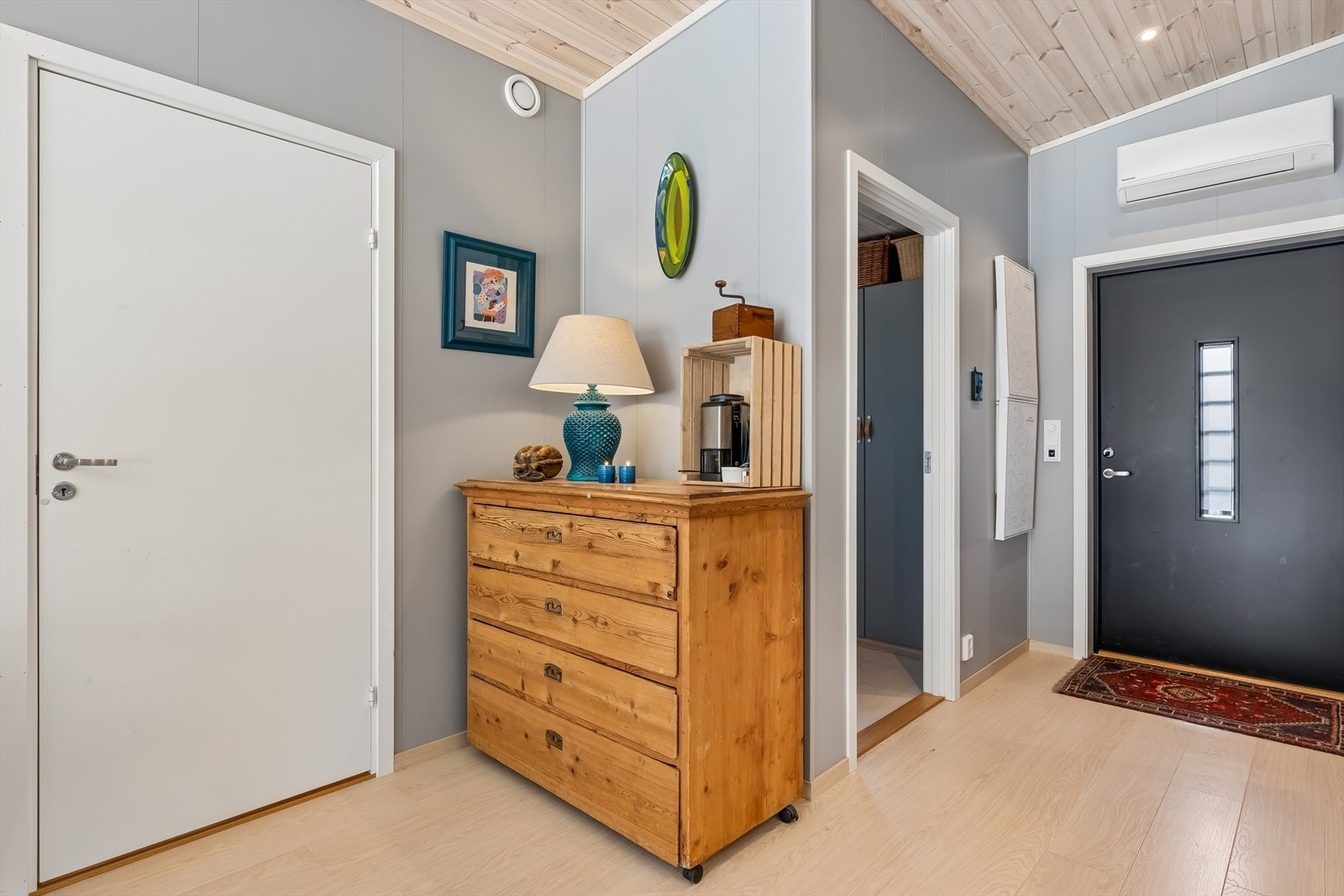 Entréen er lys og funksjonell, og leder deg videre inn i boligens åpne oppholdsrom. Bak bildene ved inngangsdøren finner du bla. sikringsskapet og teknisk skap for tv/bredbånd. Galleribilde