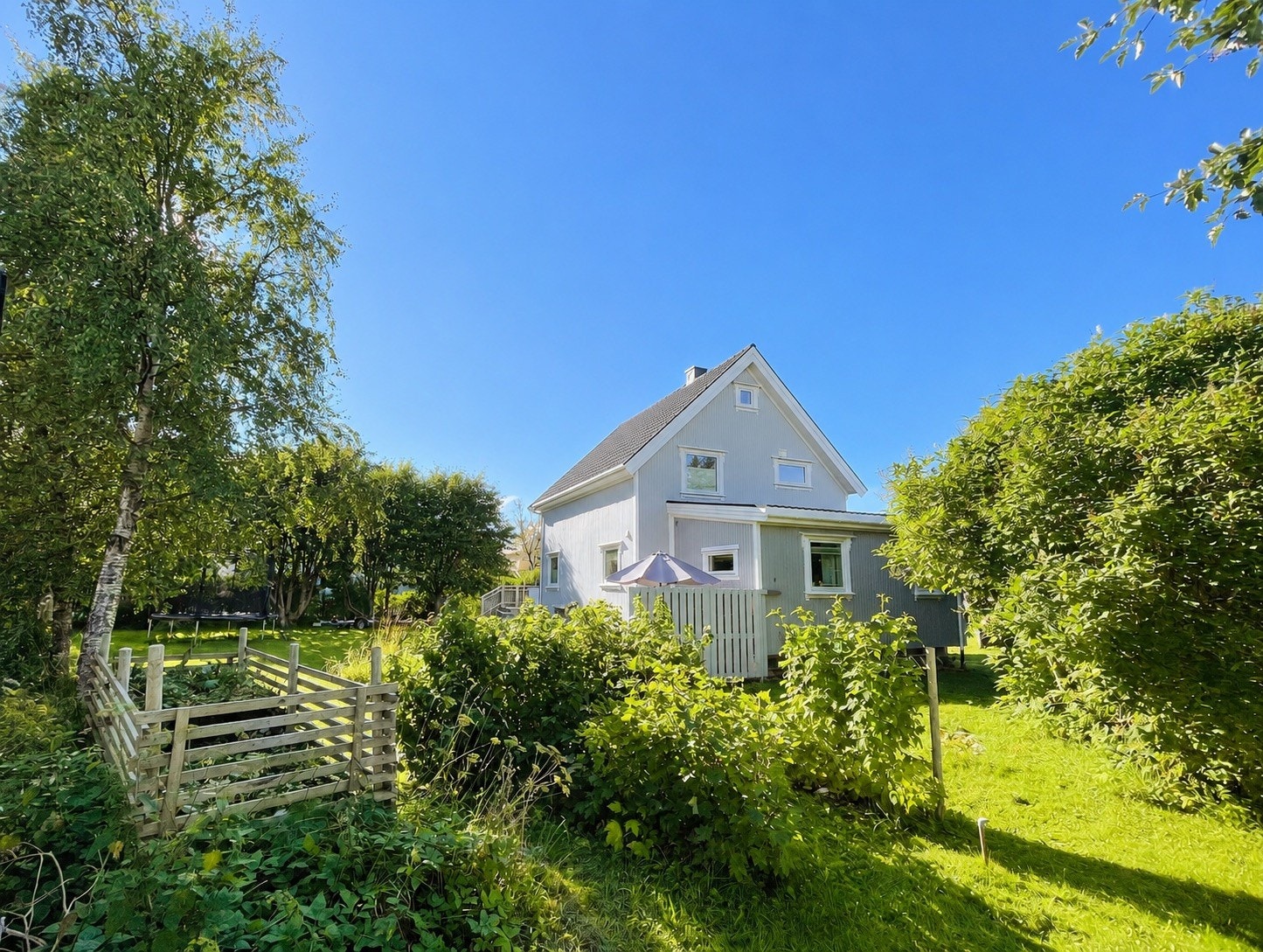 Eiendommen i sommerdrakt med den store frodige tomten. Galleribilde