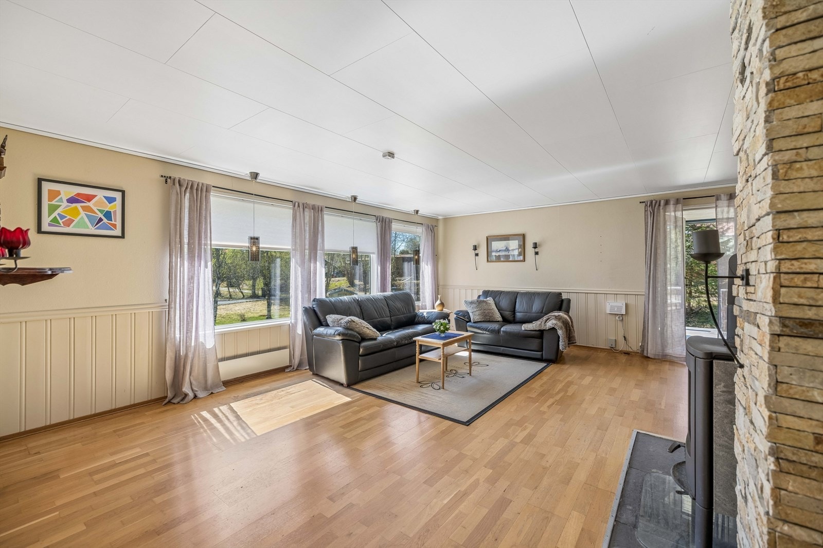 Stuen har god plass til både sofagruppe og spisebord, med overflater av parkett og malte plater. Galleribilde