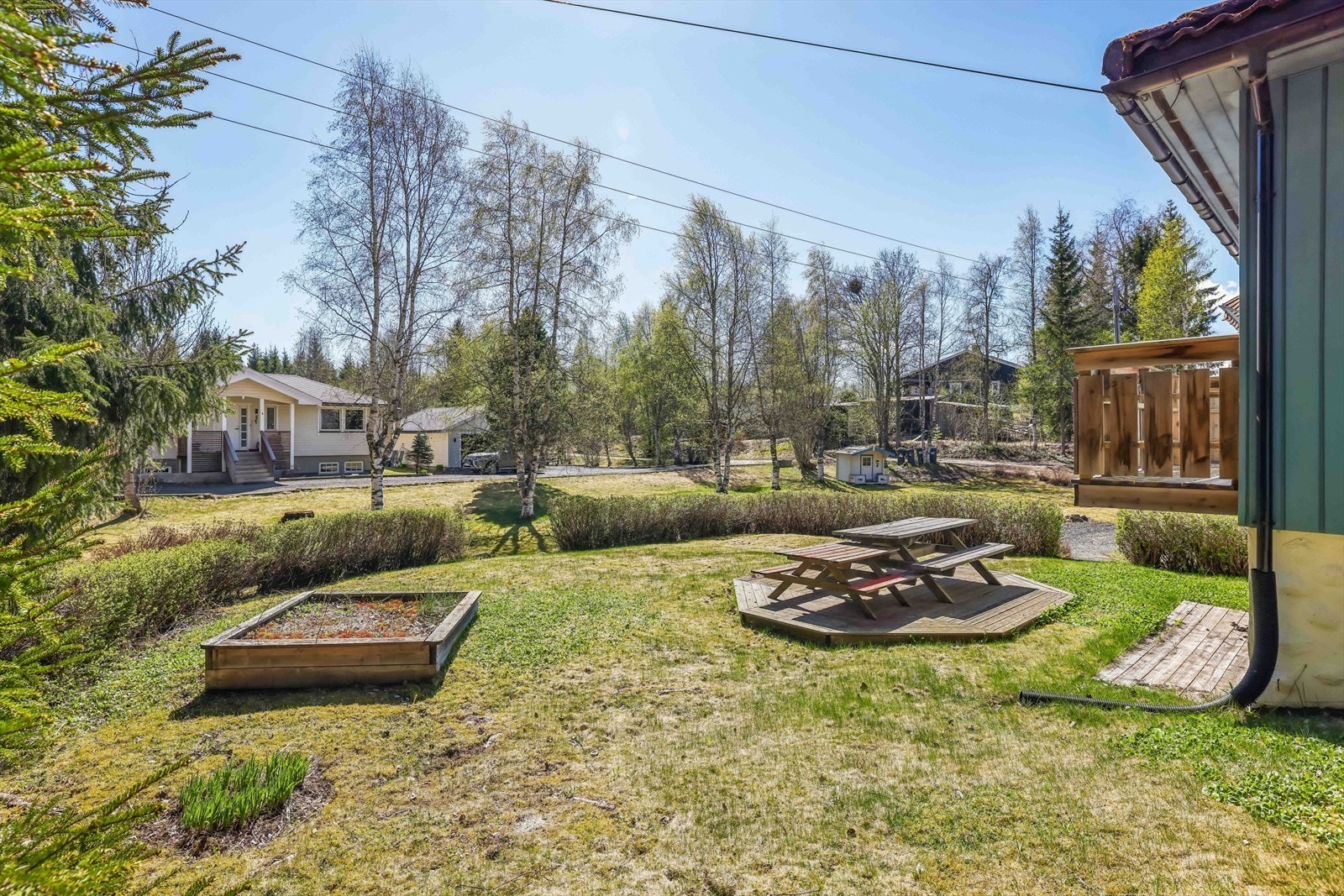Tomten er opparbeidet med plen og beplantning, og grenser mot skogsterreng i nord. Galleribilde
