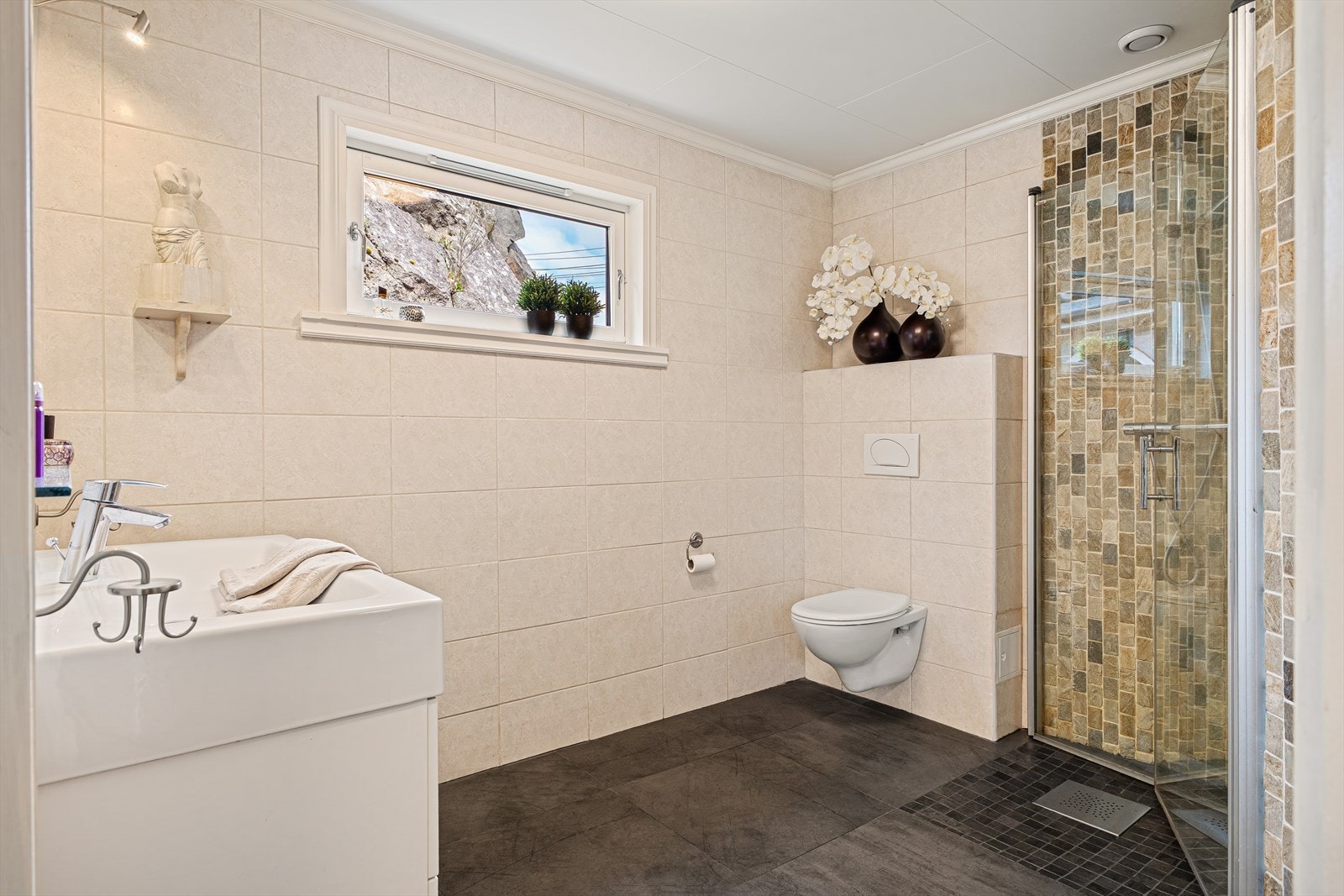 Badet er av god størrelse og inneholder baderomsinnredning med nedfelt servant, vegghengt toalett og dusjhjørne/vegger. Galleribilde