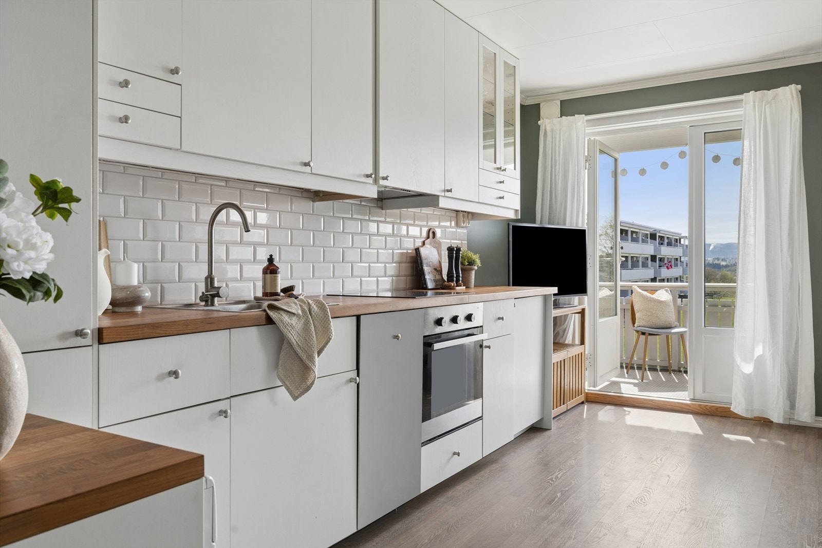 Kjøkkeninnredningen fra Ikea (2015) har godt med skap- og benkeplass, samt fliser på veggen over benken. Galleribilde