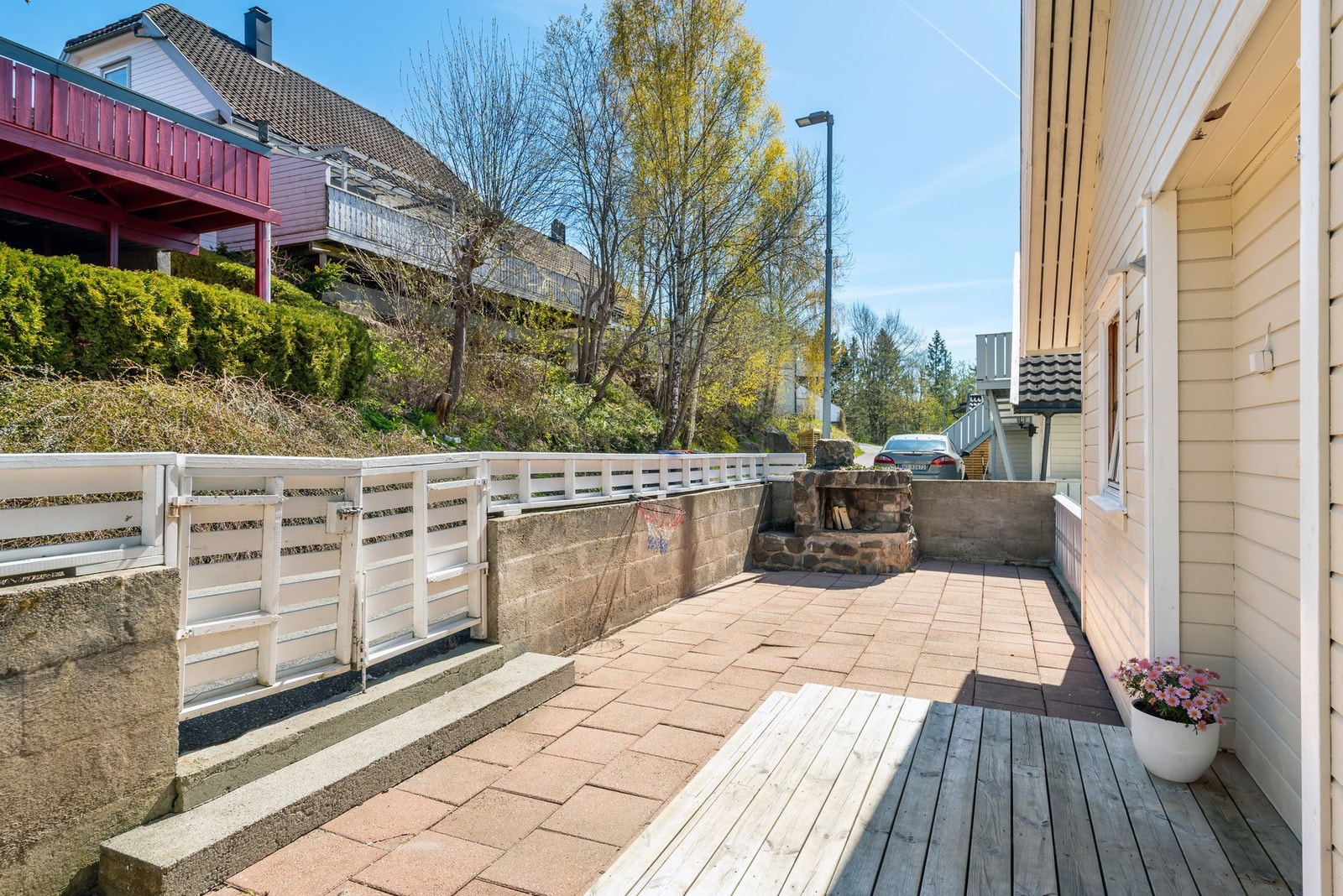 Uteområdet ved inngangspartiet. Her er det helle belagt platting, samt en oppmurt peis. Galleribilde