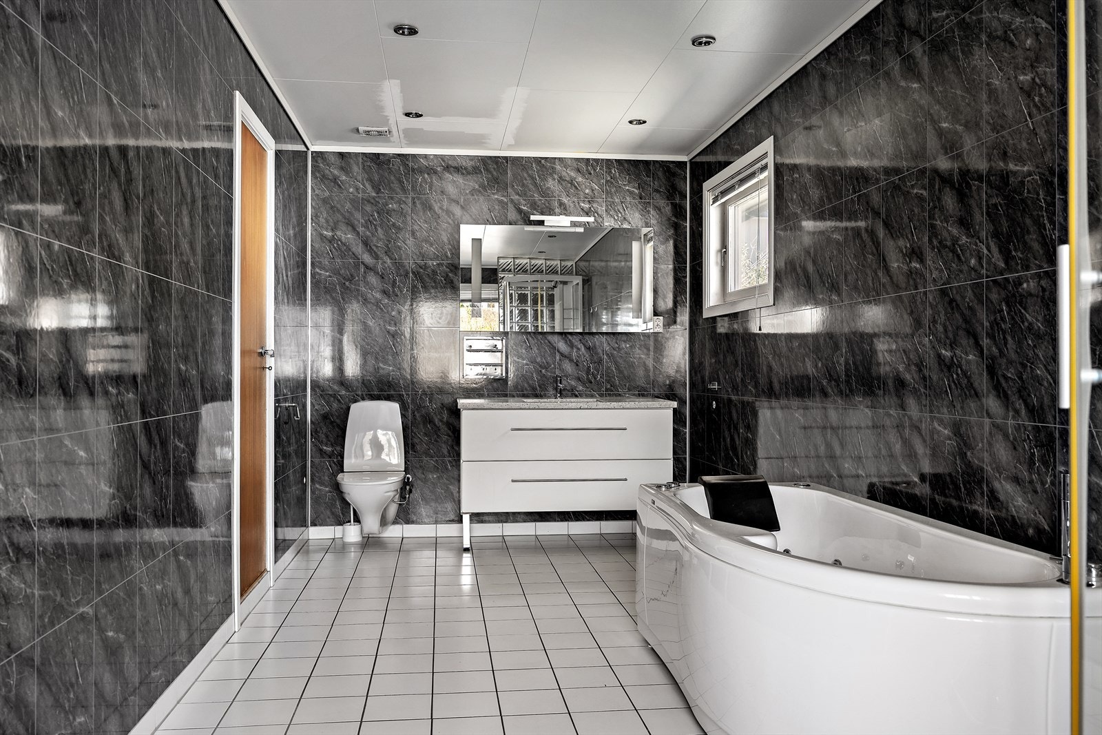 Badet har flislagt gulv, servantinnredning og opplegg for vaskemaskin. Galleribilde