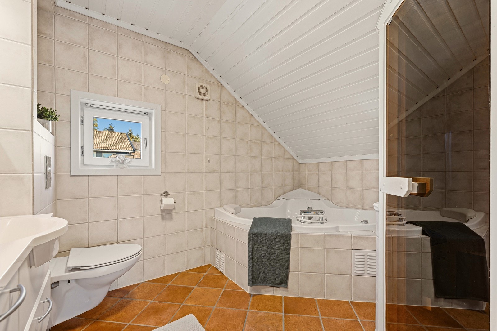 Badet er innredet med veggmontert toalett, servantinnredning og badekar. Galleribilde