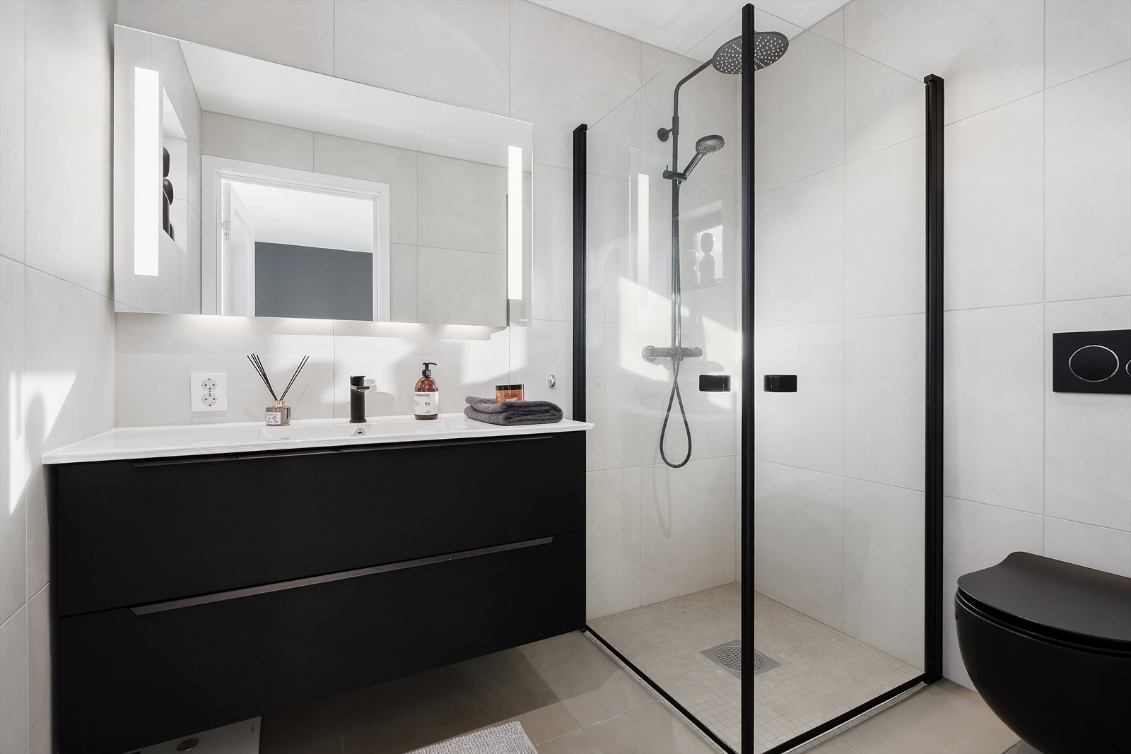 Delikat bad med moderne farge- og materialvalg. Badet er flislagt med tidsriktige 60X60 fliser i hvit utførelse med varmekabler i gulv og malt himling. Galleribilde