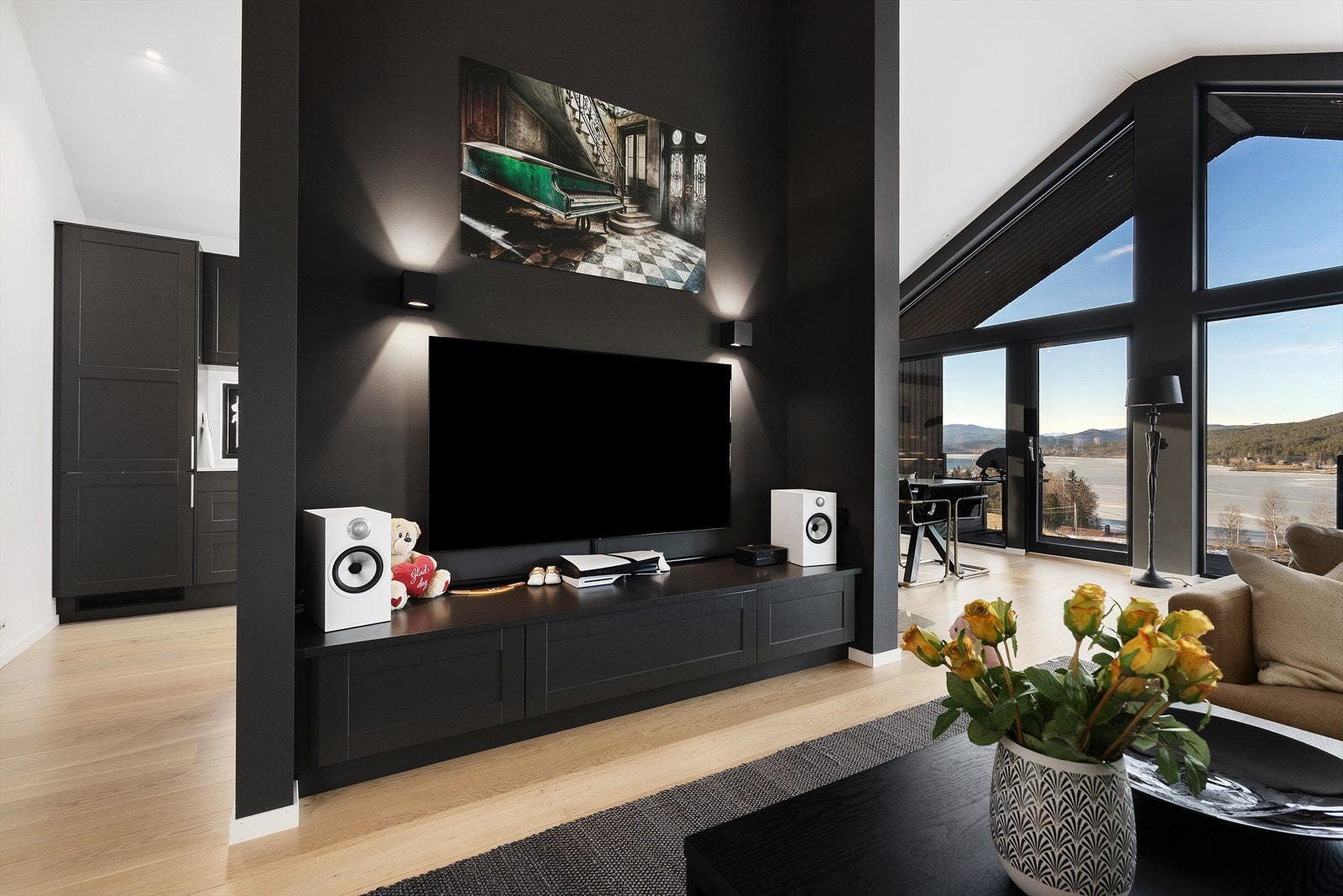 Stuen oppleves både luftig og smart innredet, der den stilrene TV-veggen fungerer som en naturlig romdeler i oppholdsarealet. Galleribilde