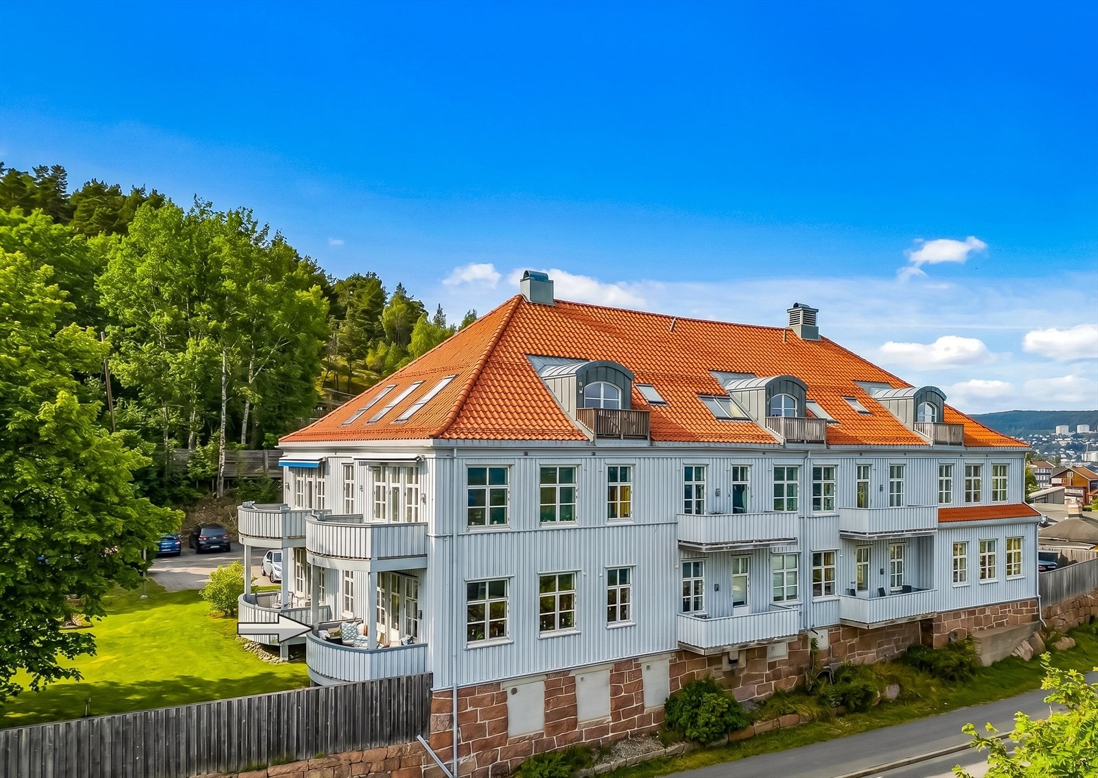 Leiligheten ligger i den tidligere Nøsted skole, en karakteristisk bygning fra 1920 som ble ombygget i 2007. Ytterveggene ble etterisolert i 2014. Sommersesong er AI-generert. Galleribilde