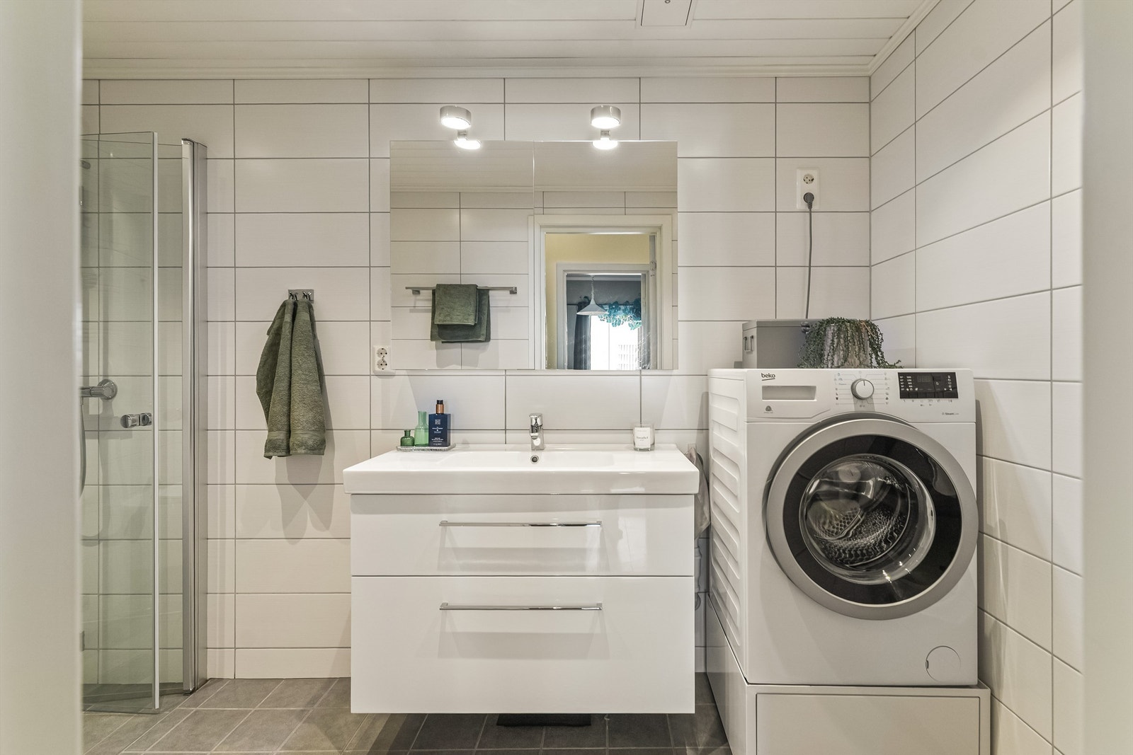 Badet er utstyrt med vegghengt toalett, dusjhjørne med glassvegger og opplegg for vaskemaskin. Galleribilde