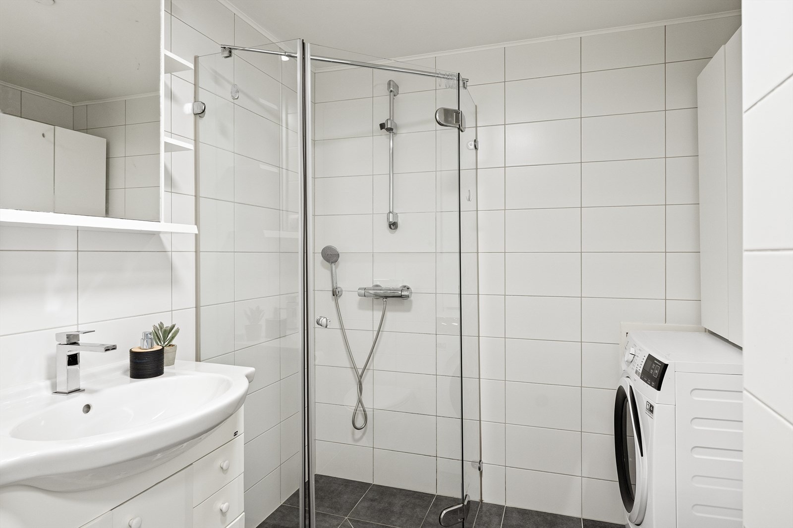 Badet er av god størrelse, og er innredet med klosett, dusjhjørne, servant med skuffer og speilskap med lys. Galleribilde