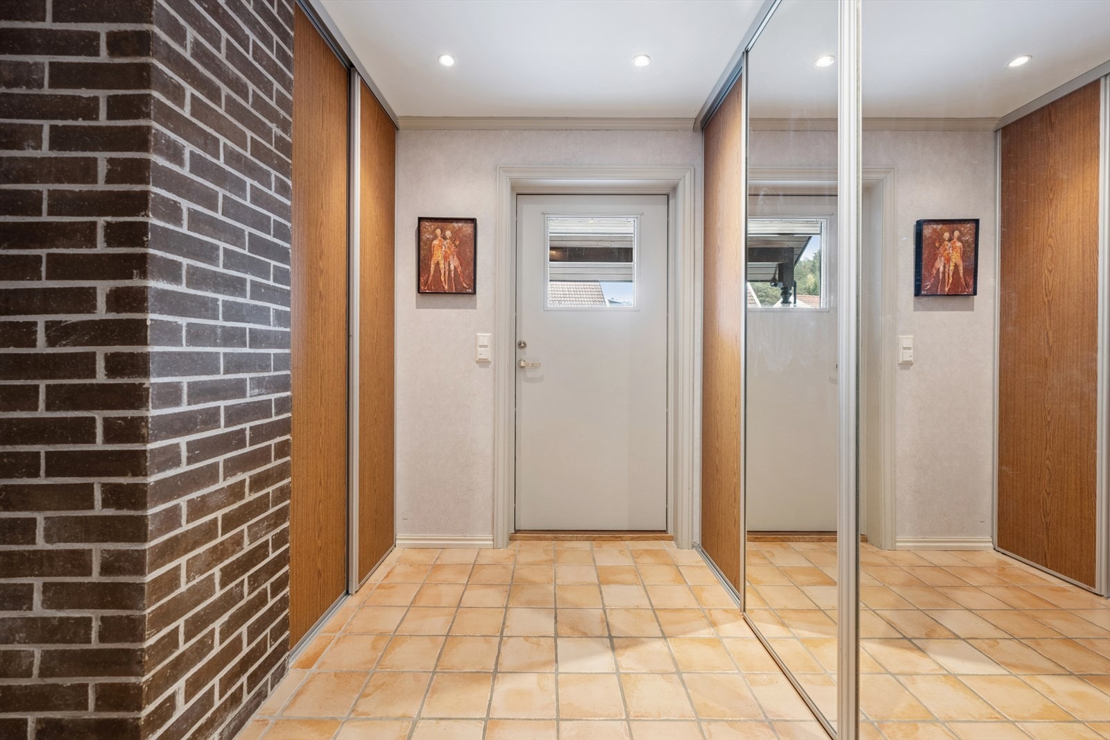 Man ønskes velkommen inn i en romslig entré/gang som er praktisk innredet med flislagt gulv og stor skyvedørsgarderobe som gir rikelig med lagringsplass til familiens yttertøy. Galleribilde