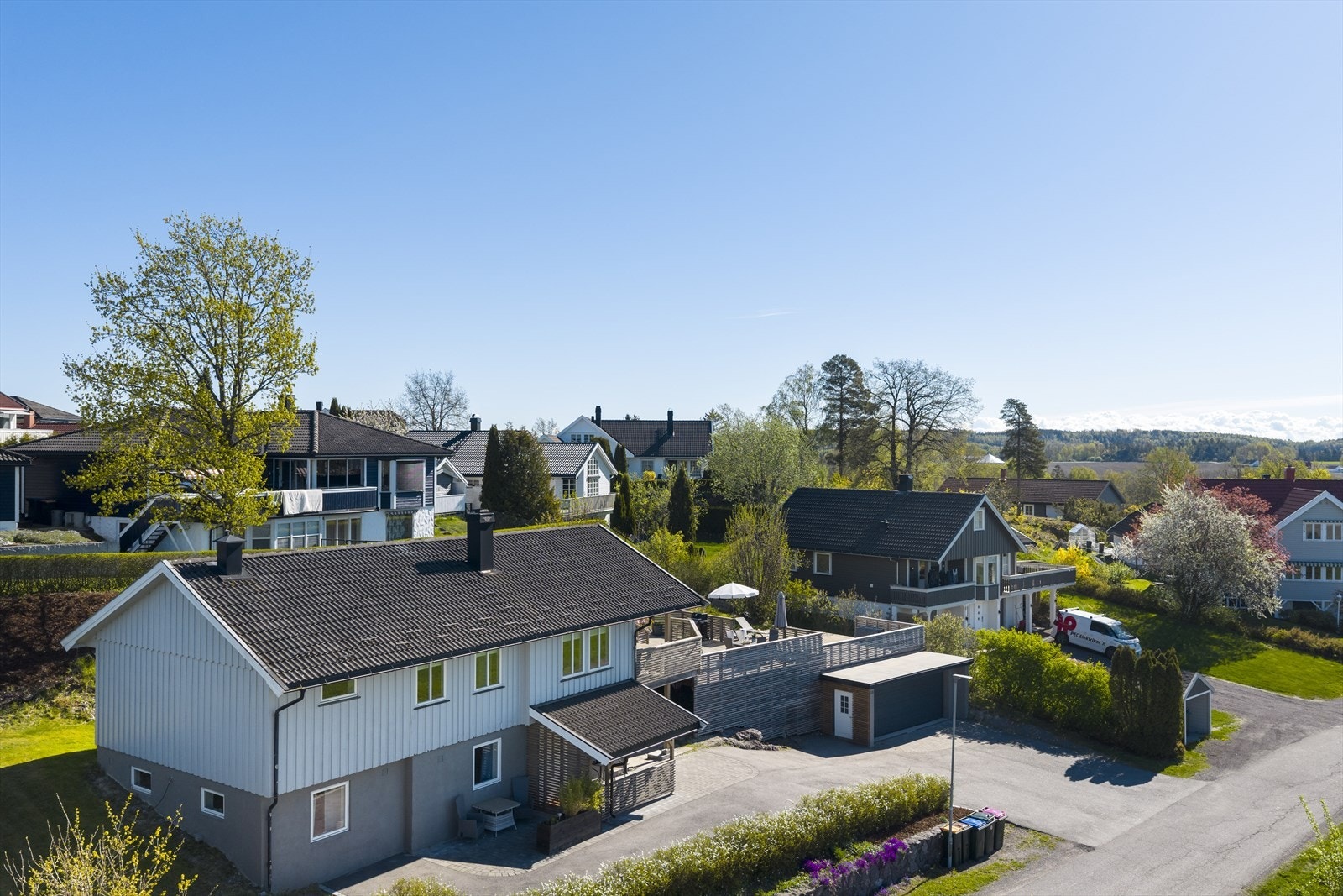 Tomten er skrånende og opparbeidet med plen, belegningsstein og hekk. Galleribilde